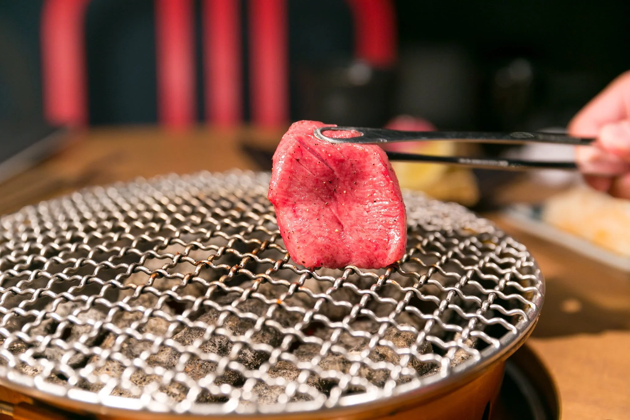 A single cut of wagyu beef held over a charcoal yakiniku grill in Japan