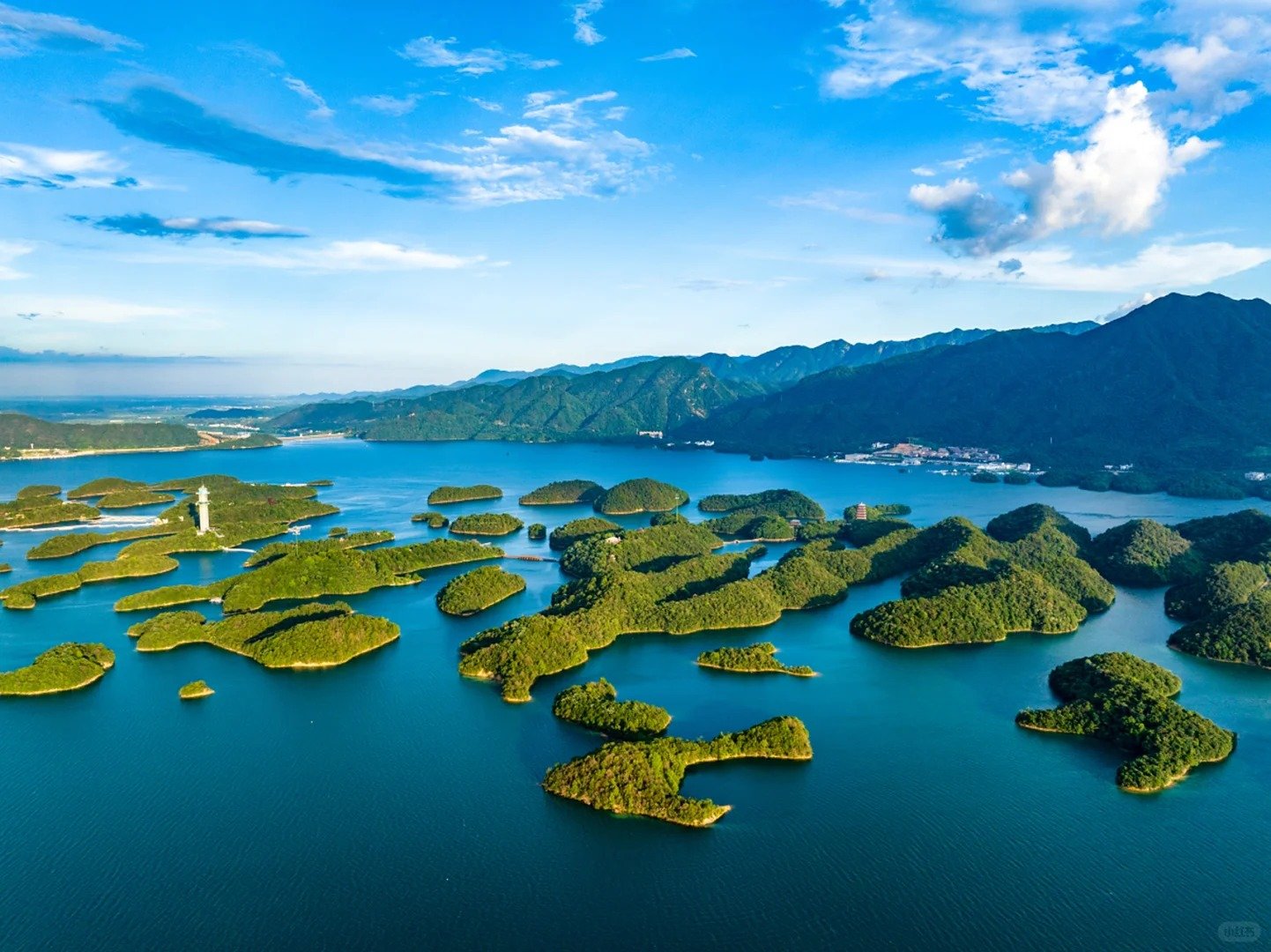 Qiandaohu Lake with many small, forested islands in the middle of the lake, and mountains in the background