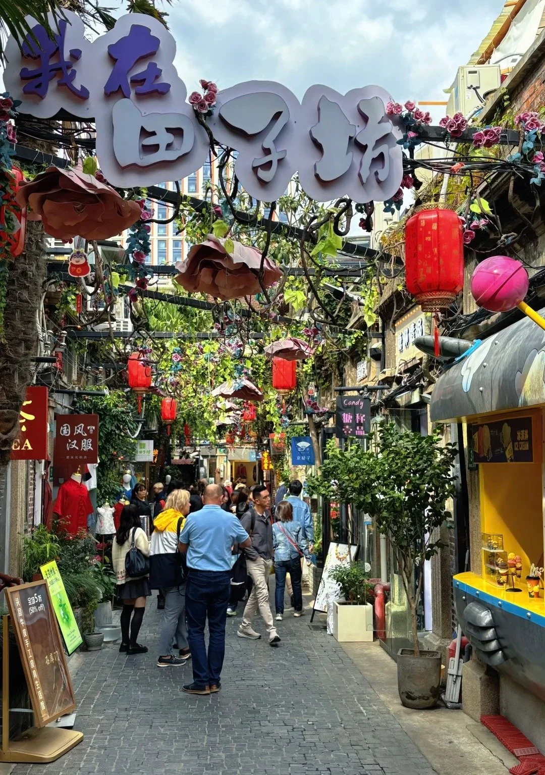 Entrance of an alleyway in Tianzifang with the name in Chinese characters above and many people browsing