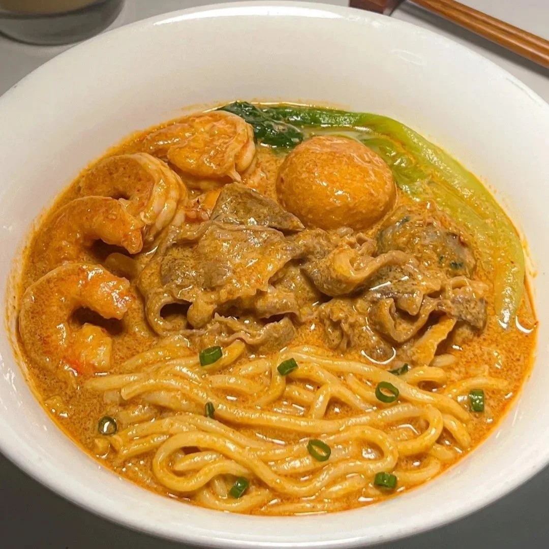 A bowl of shachamian noodle soup with fish balls, prawn and meat