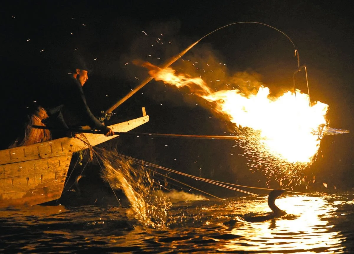 Traditional cormorant fishing by firelight on the Nagara River in Seki, Gifu, with sparks flying from the torch