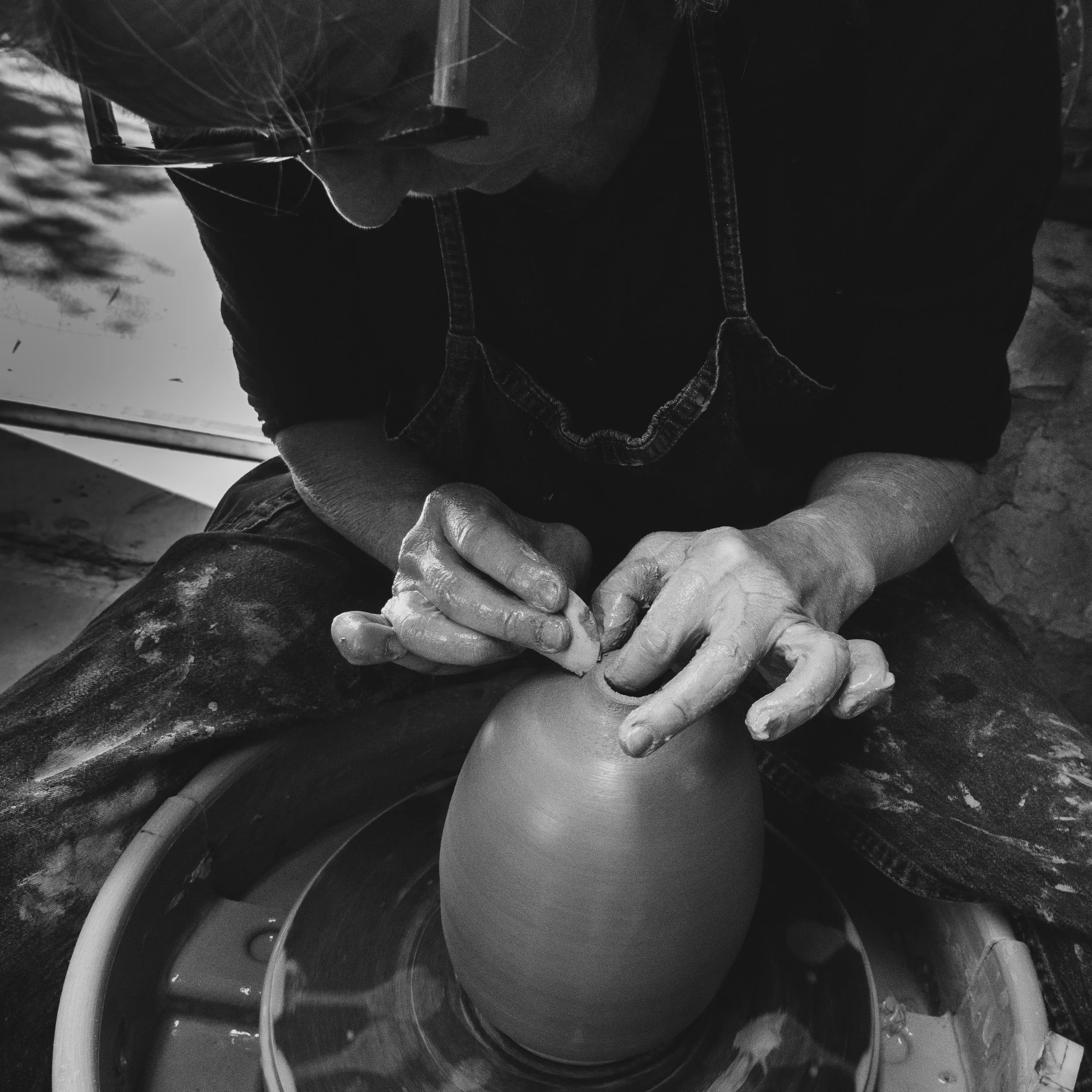 A person shaping a clay pot on a pottery wheel in a pottery studio in Echizen, Japan