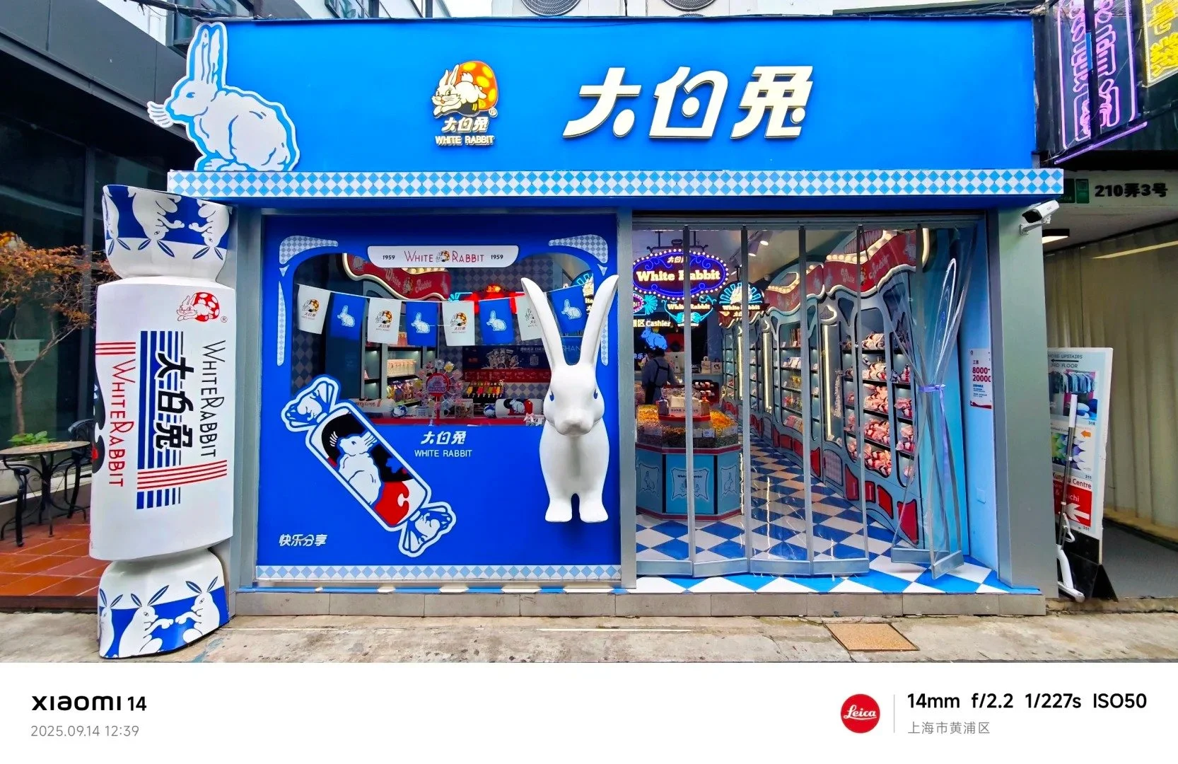 Exterior of the White Rabbit candy store in Tianzifang, with a blue facade, a big rabbit statue, and a big statue of a candy