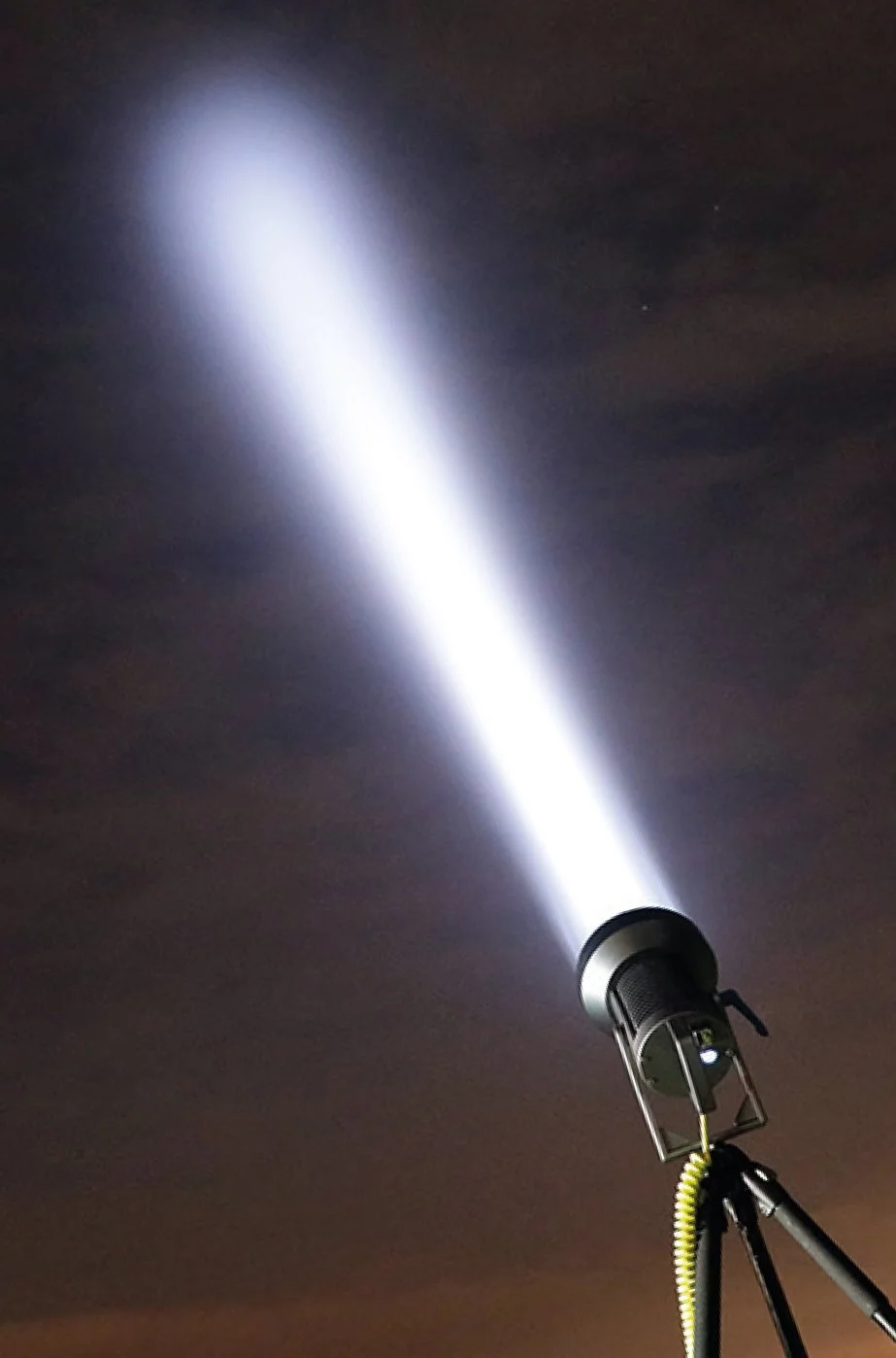 Flashlight shining a bright beam of light into the dark night sky.
