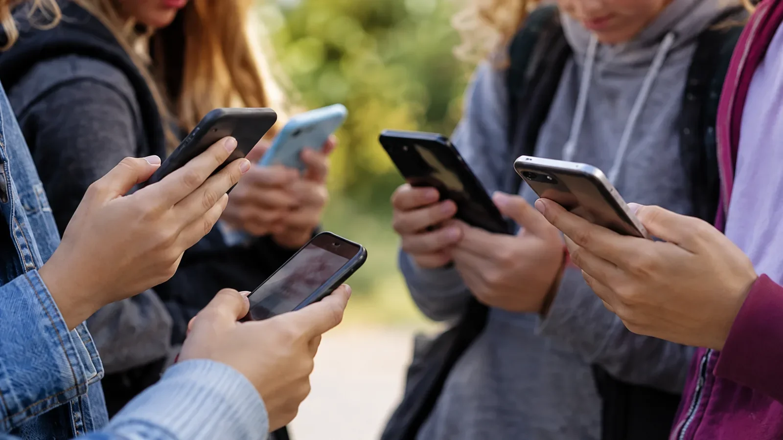 Nahaufnahme mehrerer Jugendlicher, die ihre Smartphones in den Händen halten.