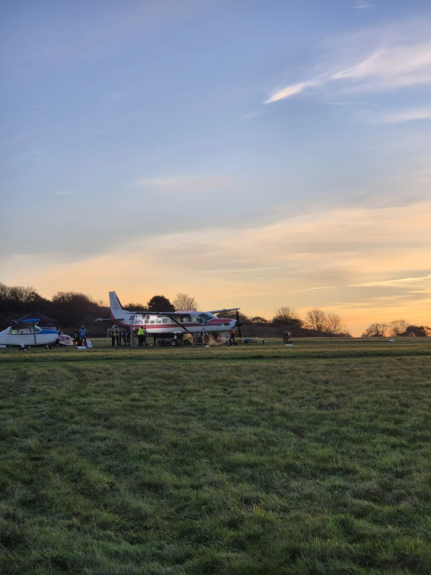 Two young men working with a professional film camera outdoors, surrounded by greenery.