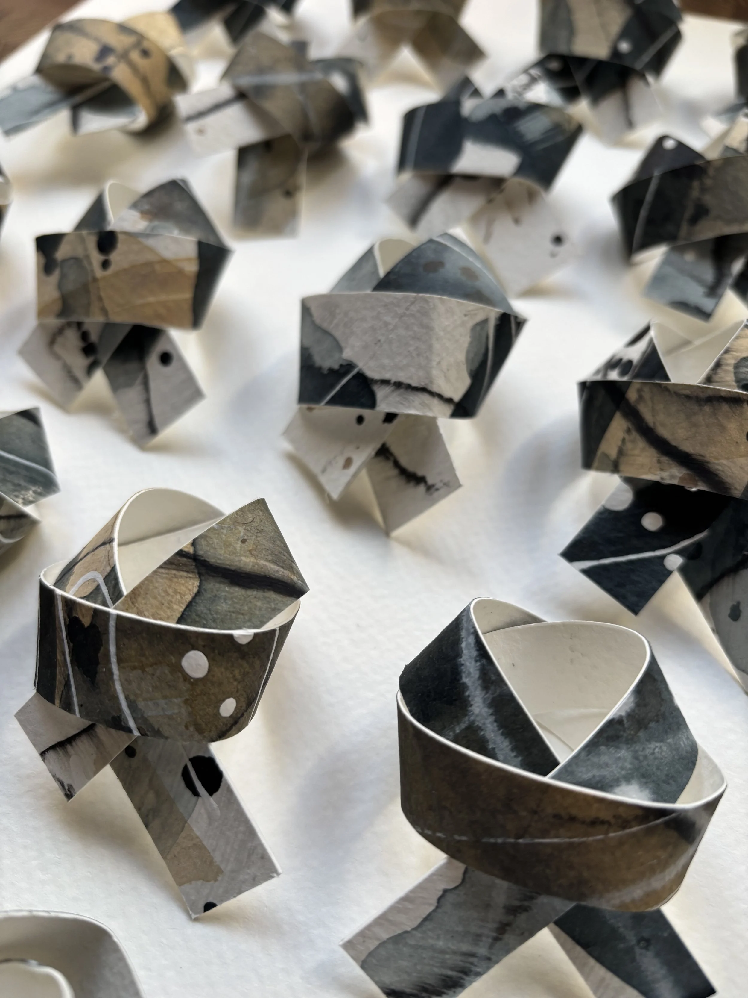Several black, white, and beige paper rings with marbled patterns, arranged on a white surface.