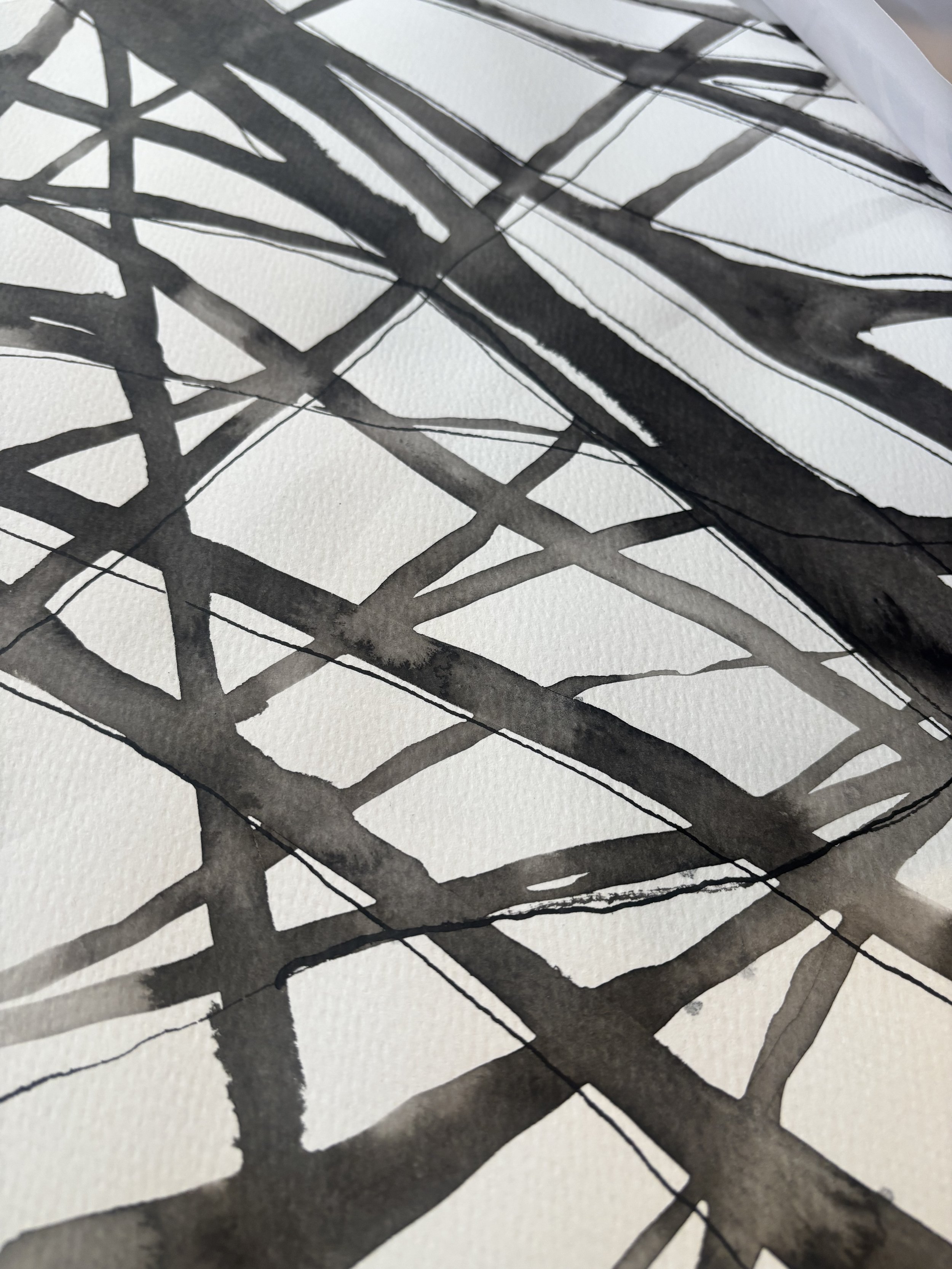 Close-up of black ink strokes on white textured paper, creating an abstract geometric pattern.