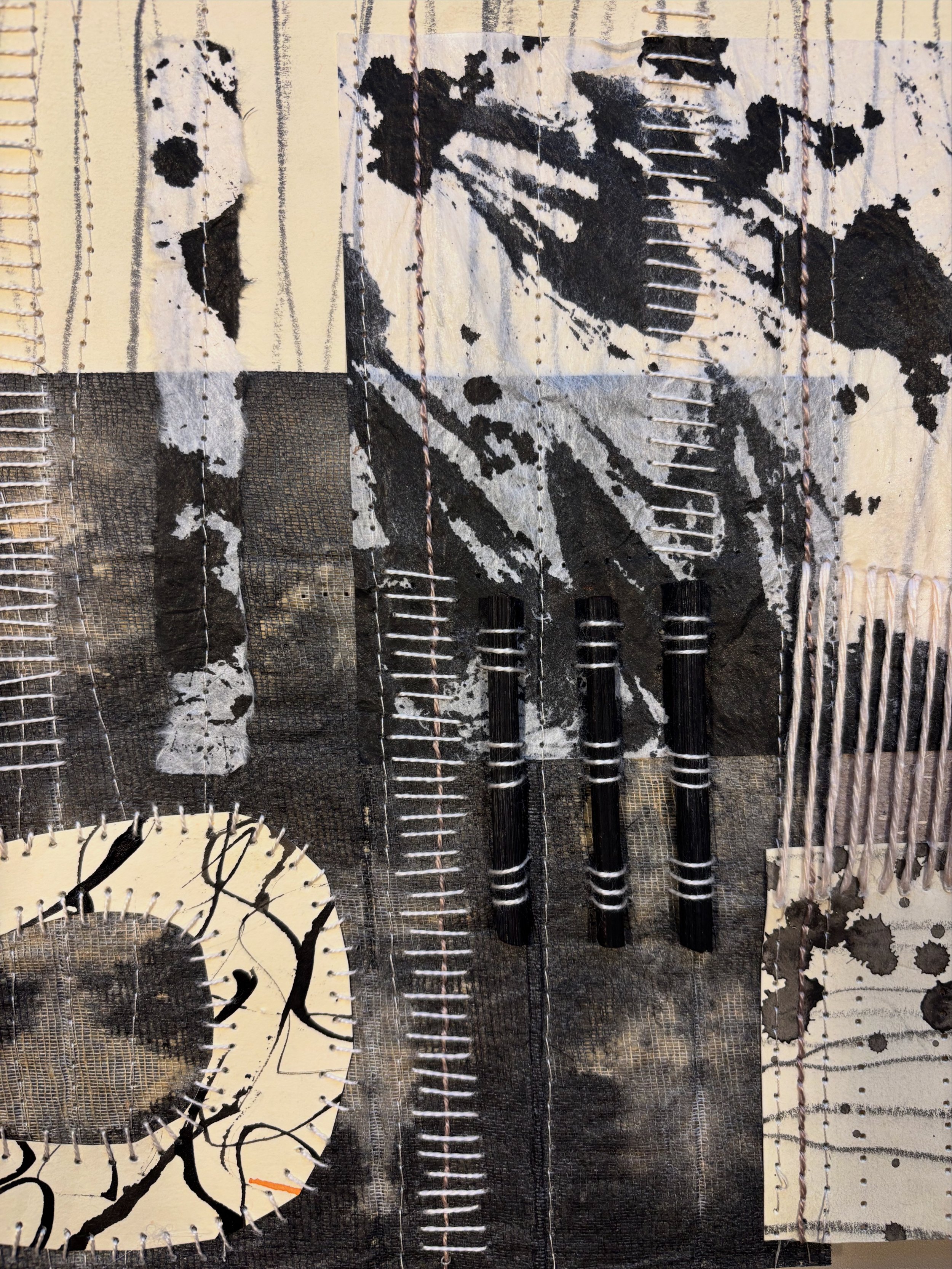 Mixed media artwork featuring black and white abstract patterns, stitched lines, and various textured elements.