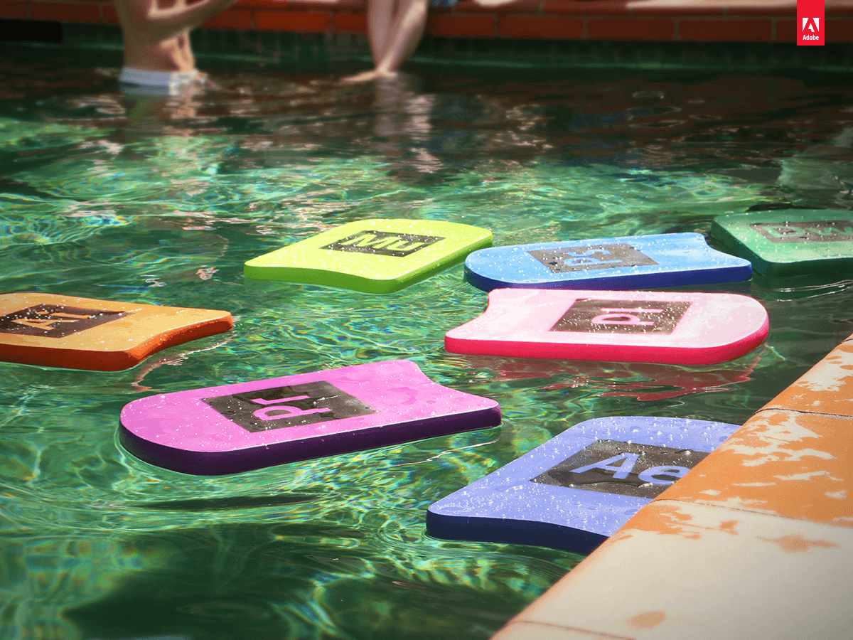 Colorful pool floats with adobe program symbols floating in a swimming pool.