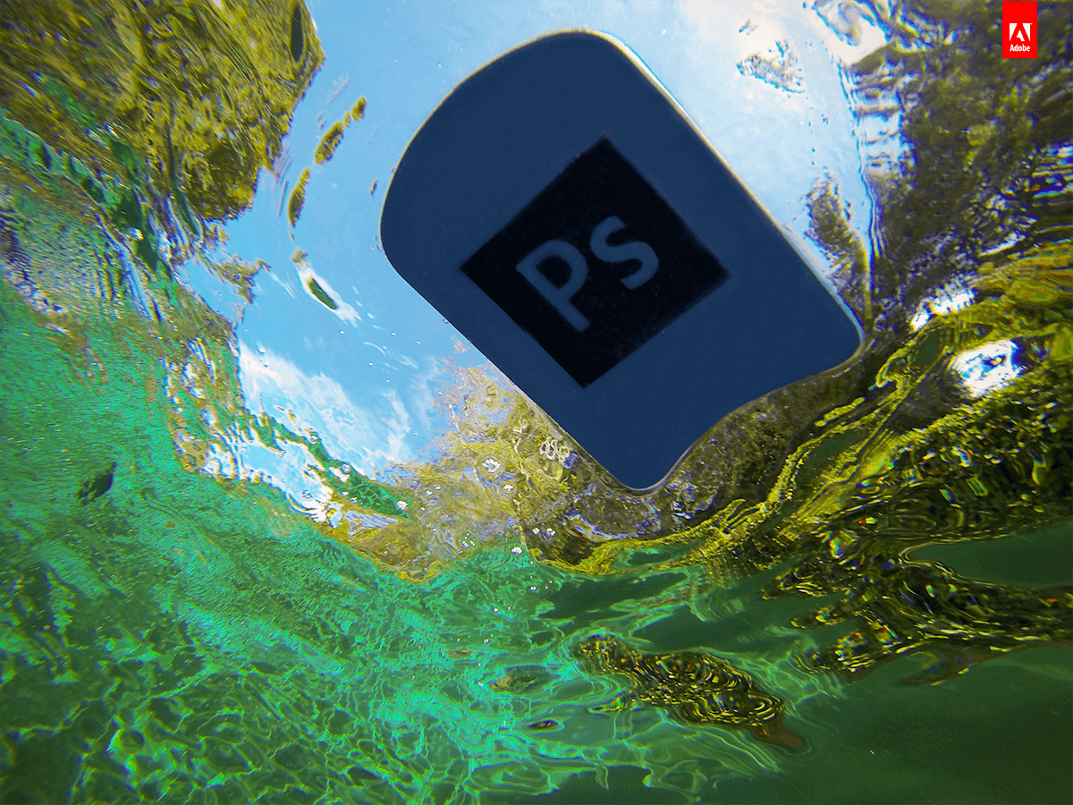 An underwater shot showing a Adobe Photoshop (PSD) pool floaty floating in the water. The water is clear with greenish hues, and the sky and trees are visible above the water surface.