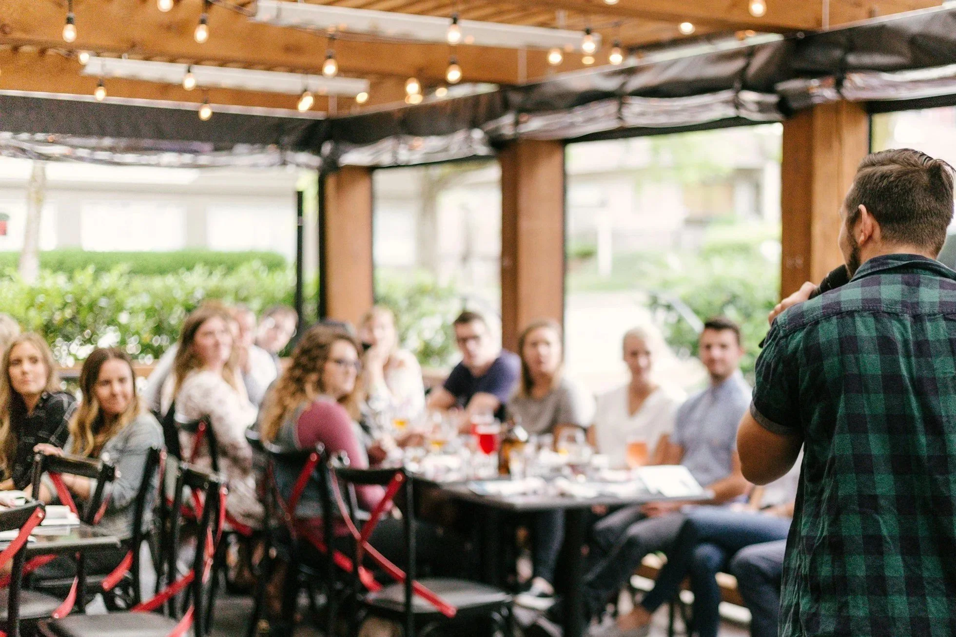 A modern house on a hillside in front of snow-capped mountains under a cloudy sky.