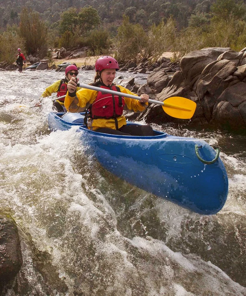 Students paddling a raft through rapids on a Venture Outdoors Co. river expedition.