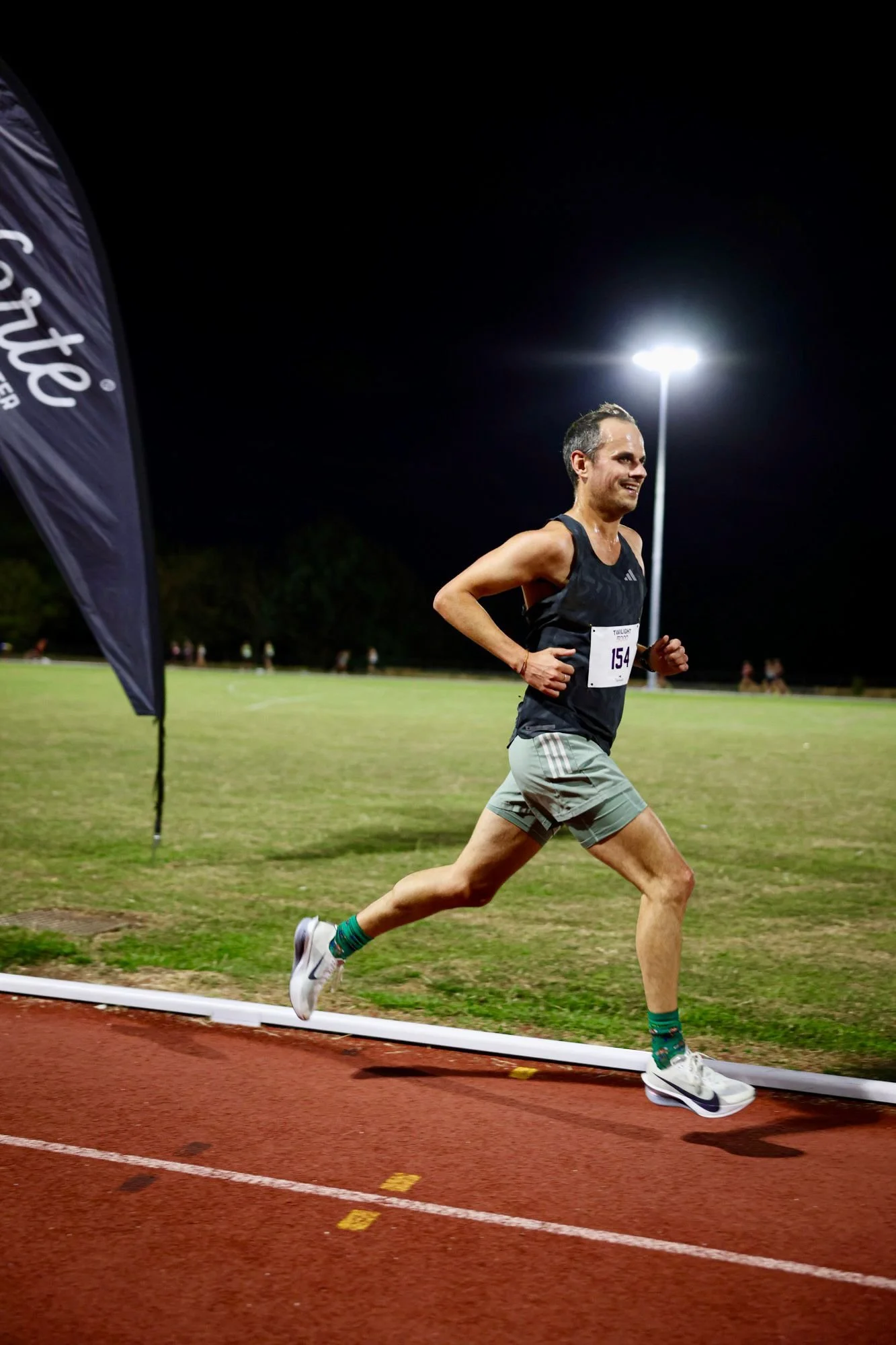 Scene of a mountainous landscape with snow-capped peaks, green rolling hills, and modern buildings in the foreground under a cloudy sky.