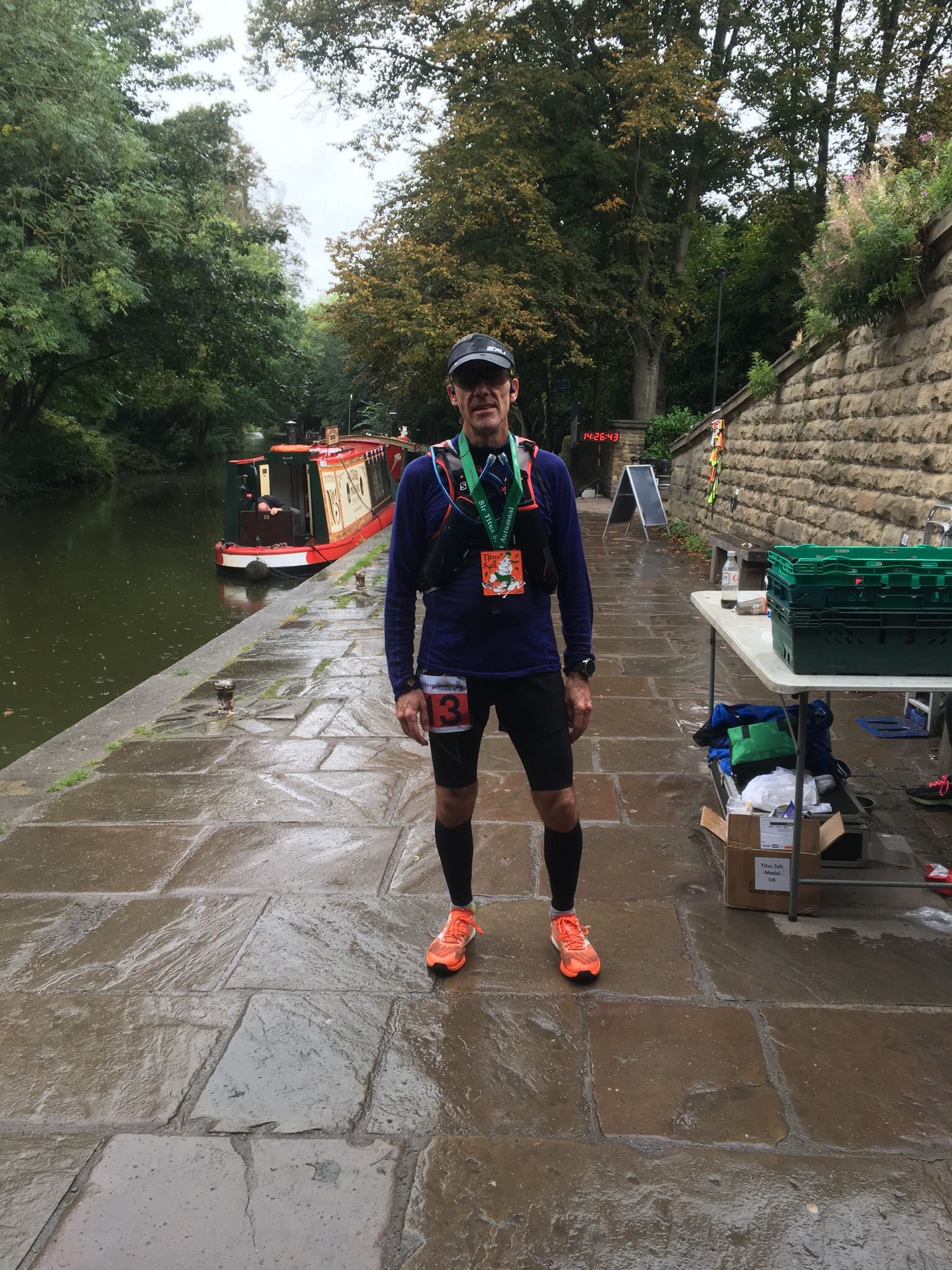 Scenic landscape of a lake surrounded by rolling hills and tall mountains under a cloudy sky.