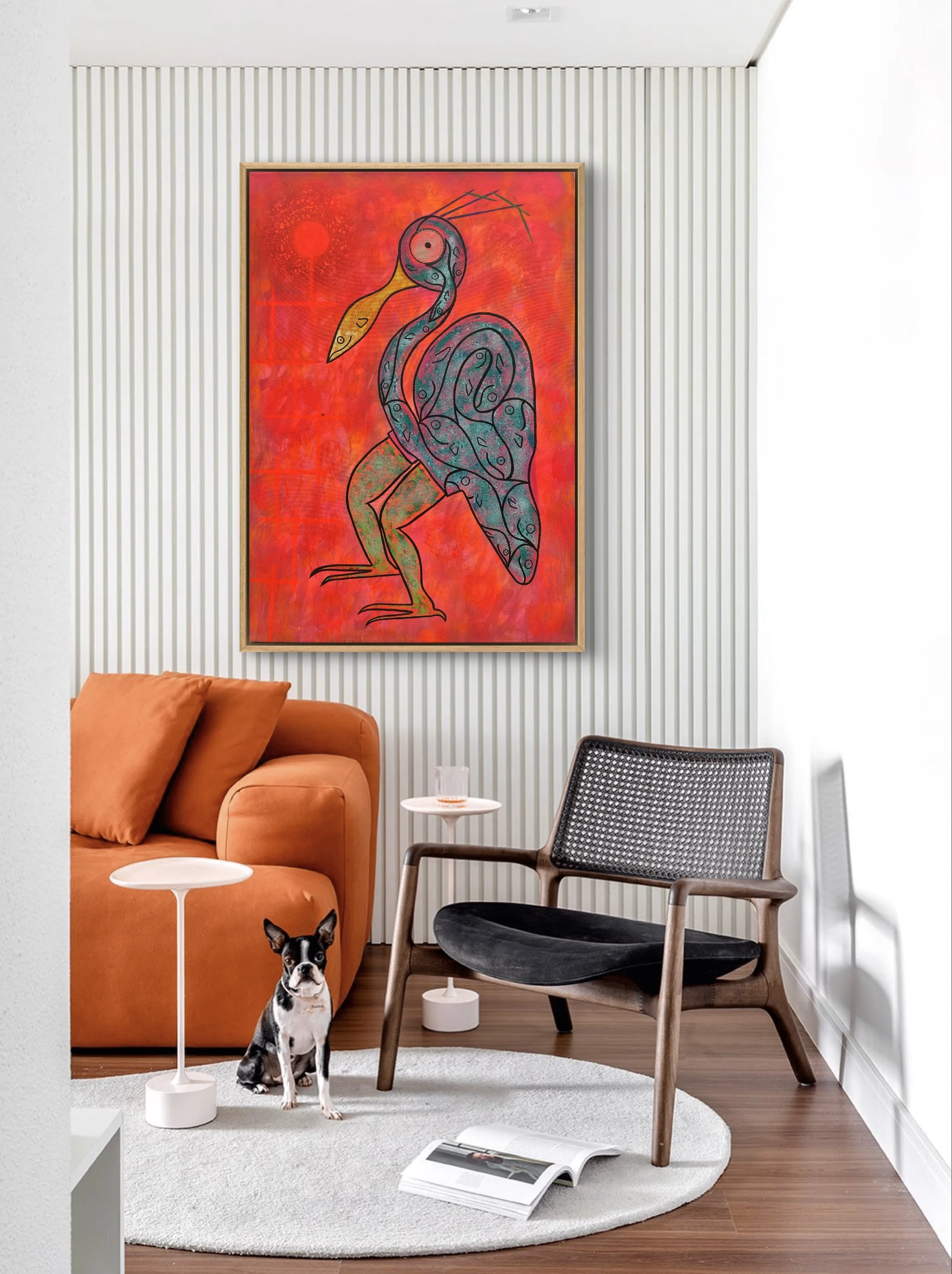 Modern living room with a large colorful abstract painting of a heron on the wall, an orange sofa with pillows, a black and wood armchair, a small white side table, a glass of water, a white circular side table, a small dog, and an open magazine on a round white rug.