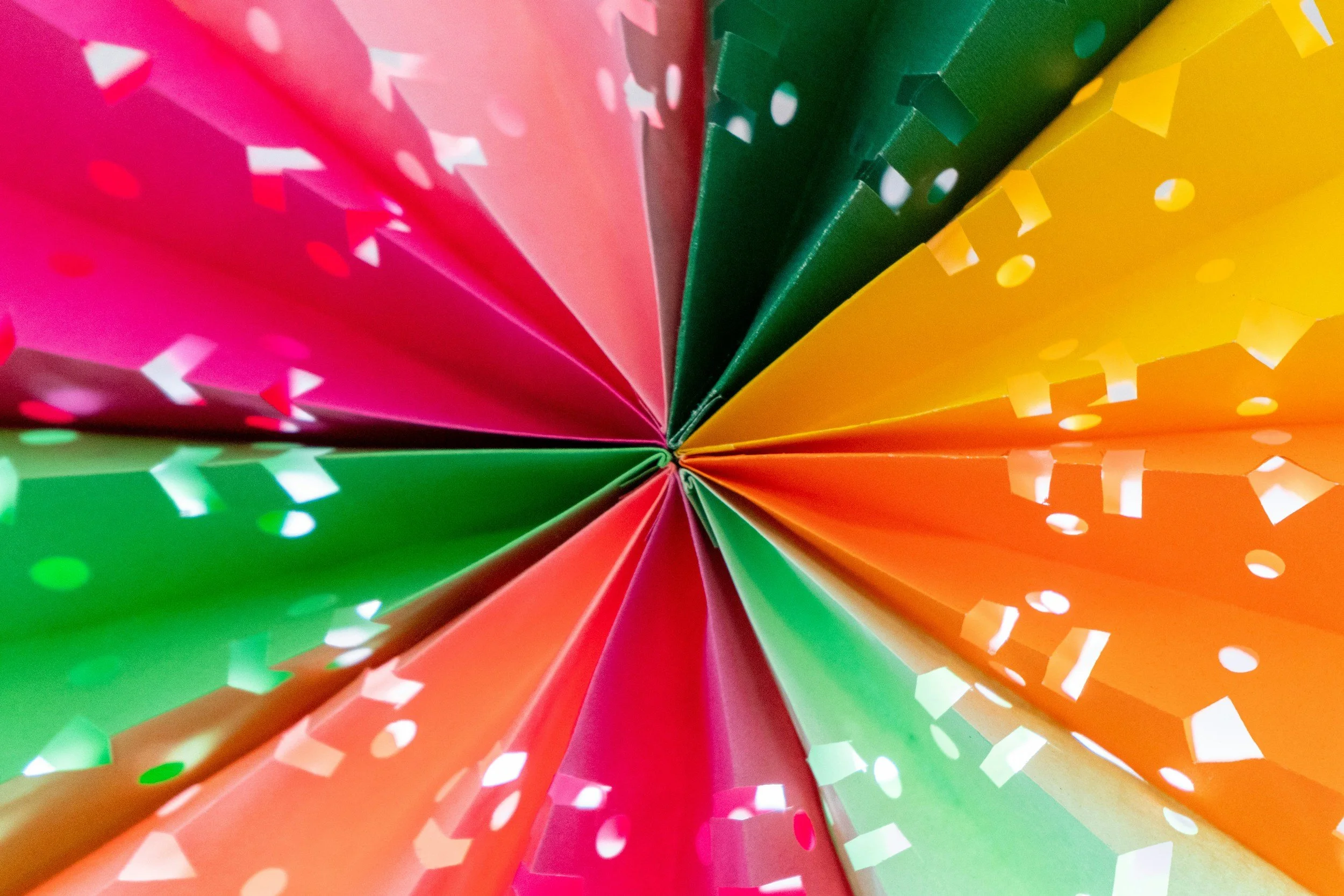 Colorful paper party hats with confetti, viewed from the bottom looking up.