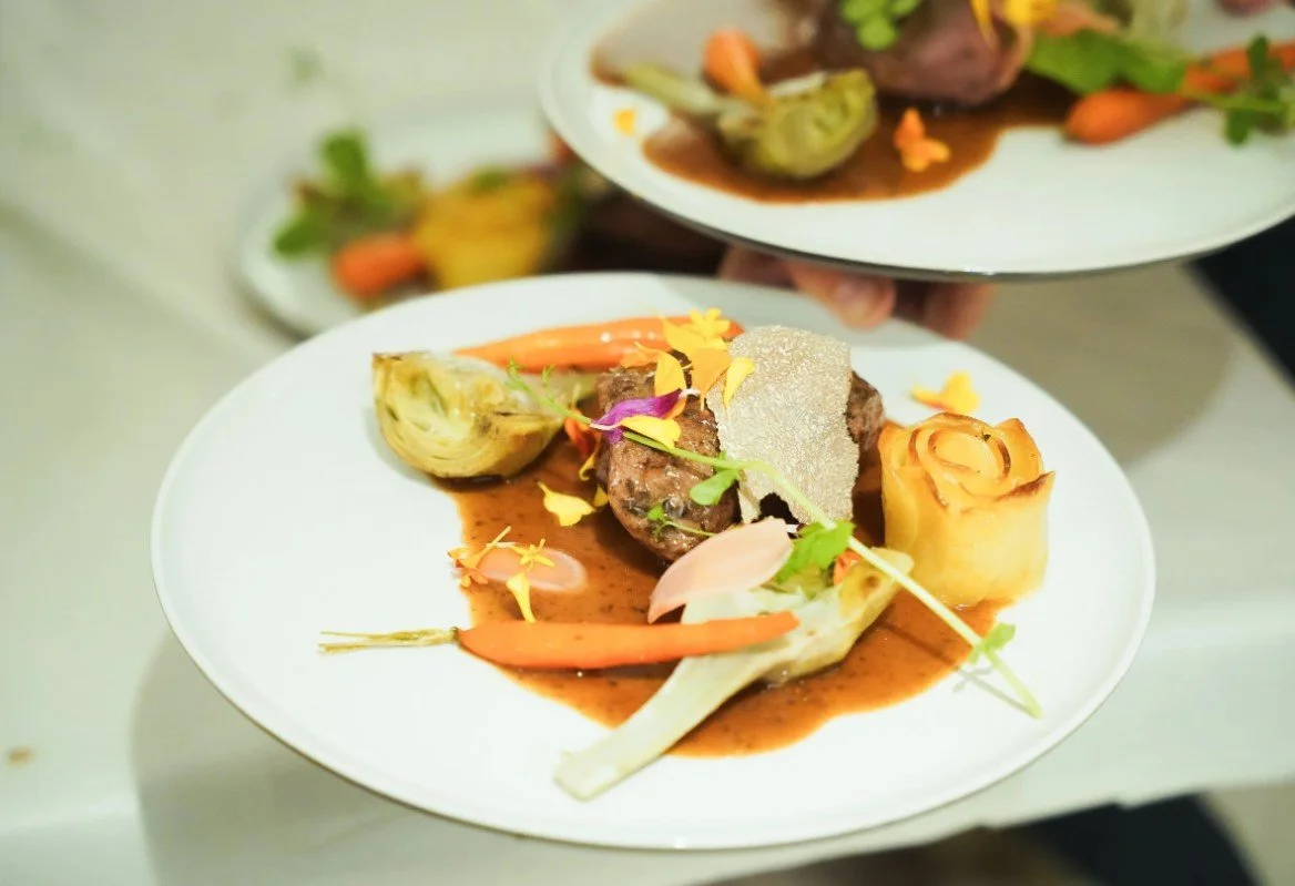 Assiette avec un filet de viande, légumes, une rose en purée, et garniture florale