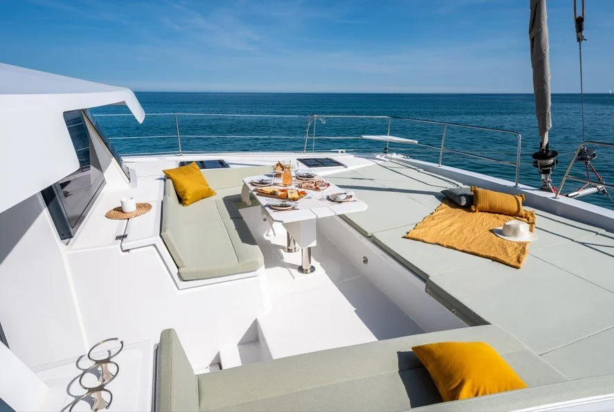 Terrasse de yacht avec coussins jaunes et table avec petit-déjeuner, vue sur la mer.