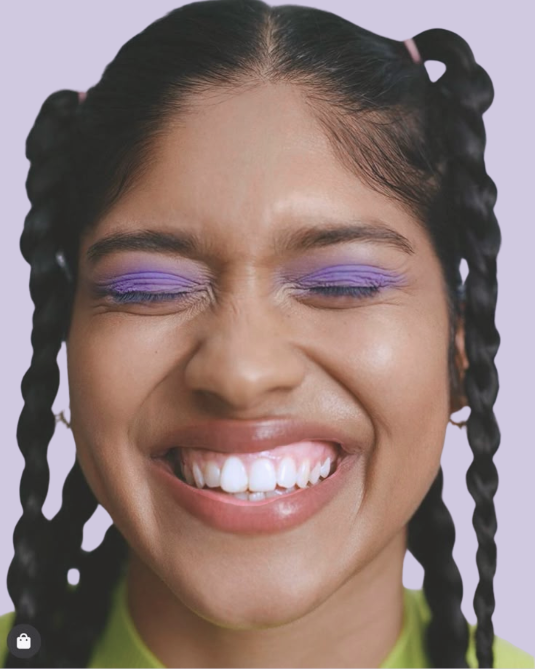 Close-up of a woman smiling with closed eyes, dark hair, and clear skin