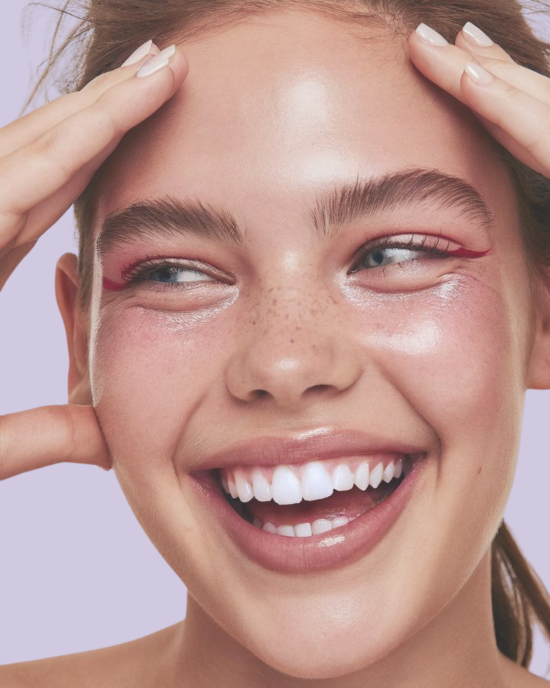 Close-up of a smiling Black woman with short hair and gold eyeshadow, showing her teeth.