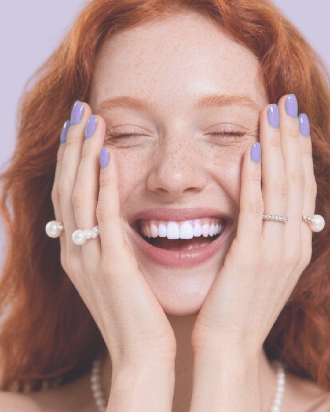 A woman laughing with her eyes closed and hand on chest, in black and white.