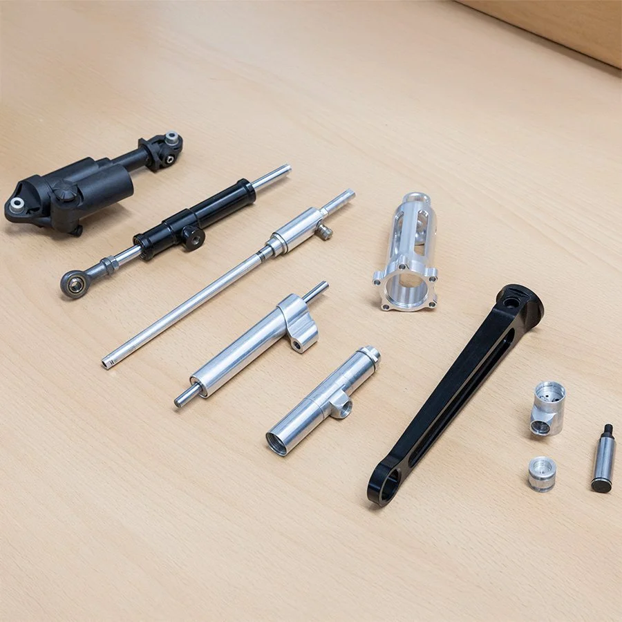 Verschiedene metallische Komponenten und Teile auf einem Holztablett, vermutlich Teile eines mechanischen oder technischen Geräts.