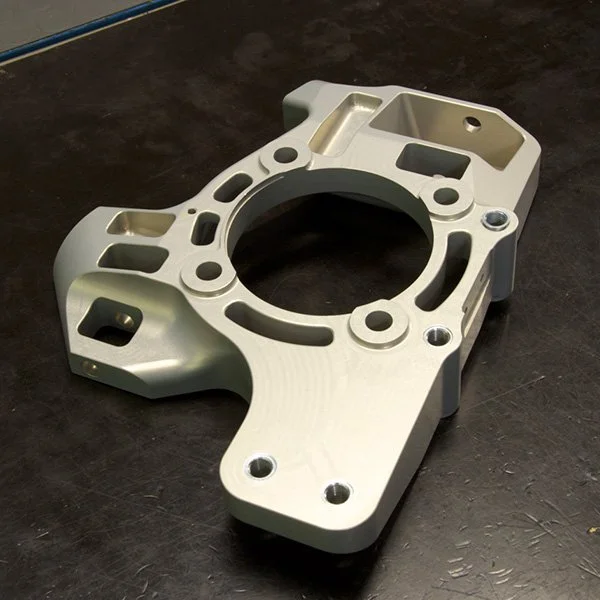 Metallteile, vermutlich ein Maschinenteil oder Bauteil für technische Geräte, auf einer dunklen Oberfläche.