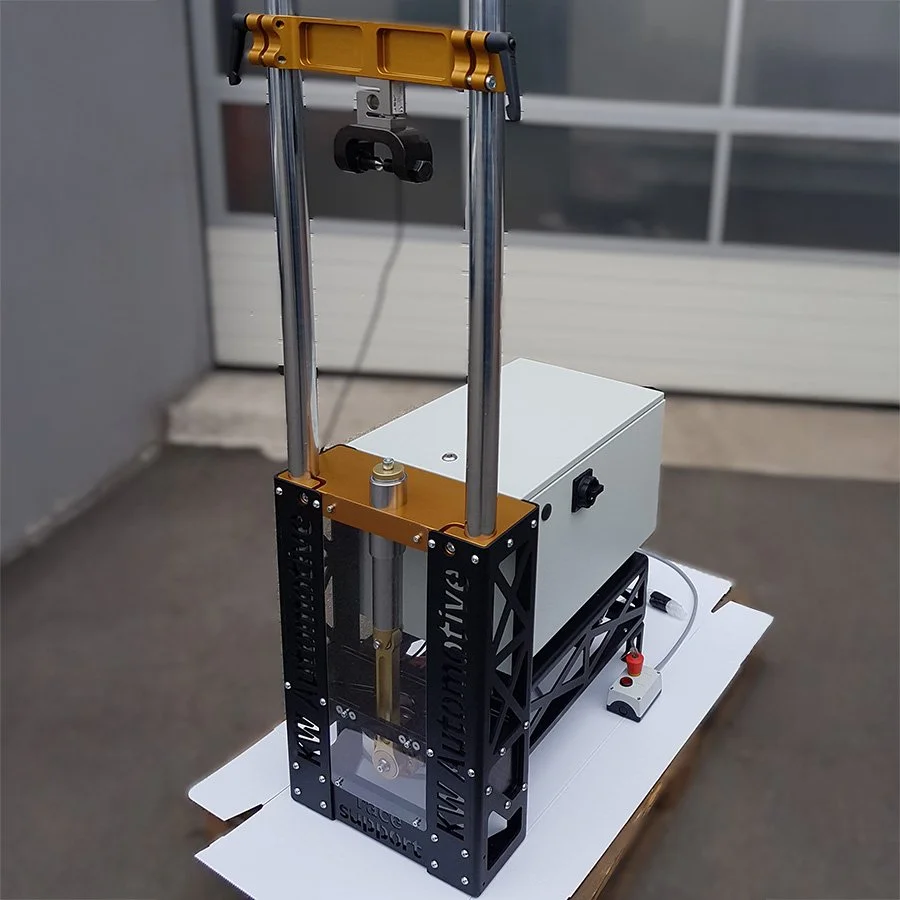 Ein kinetisches Spielzeug oder Experimentiergerät mit Metallrahmen, einer Box, einem Motor und einer Stange, das auf einem weißen Tisch steht.