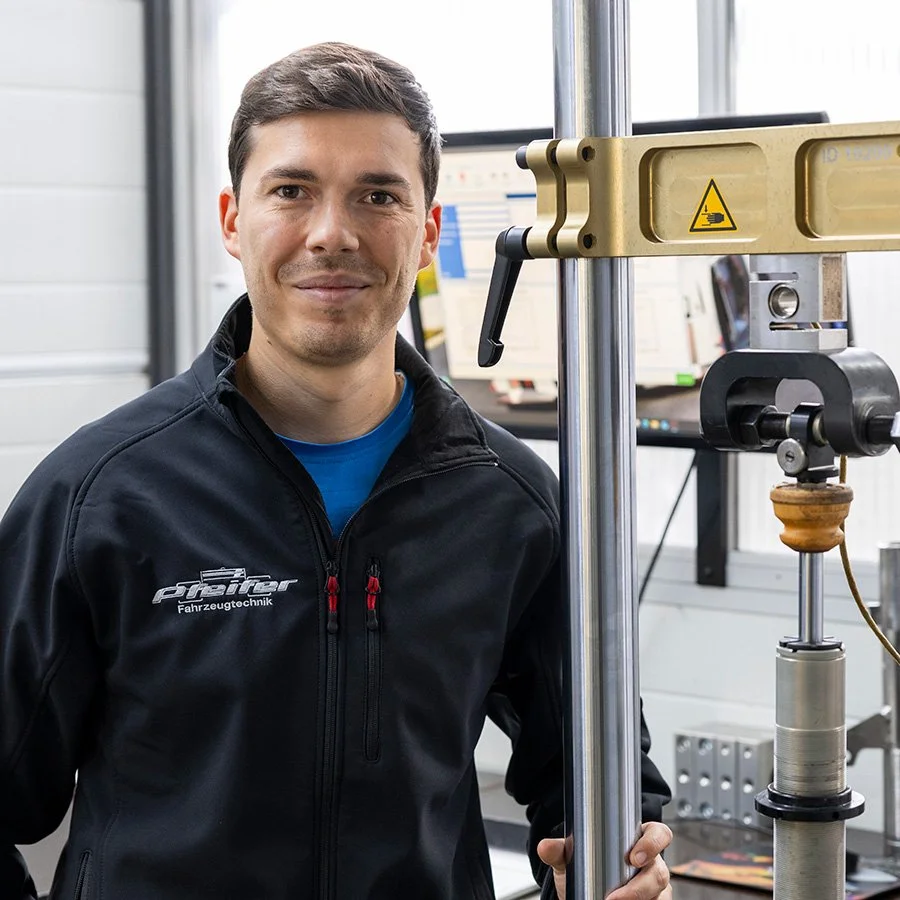 Junge Ingenieur in dunklem Jacke steht neben einem technischen Gerät in einem Forschungsraum.