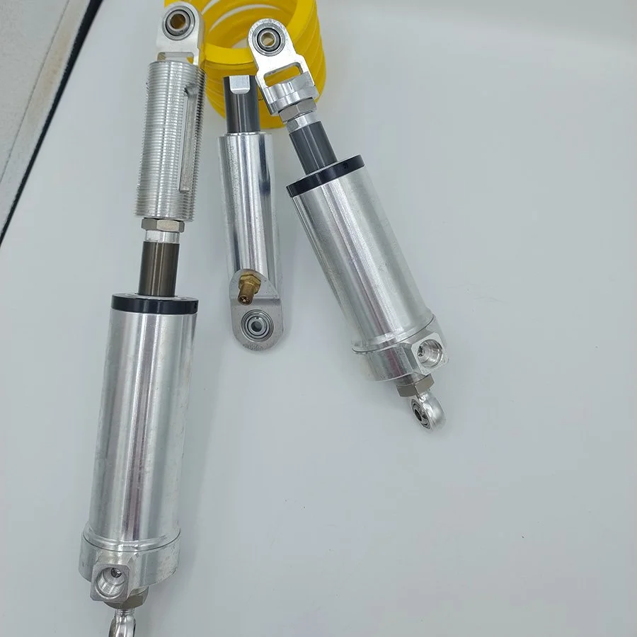 Zwei Metallfederbeine und eine Stoßdämpfer auf einer weißen Oberfläche.