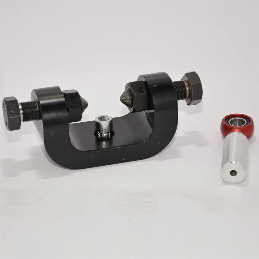 Ein schwarzes mechanisches Werkzeug mit Schrauben, zusätzlich ein rotes Ersatzteil mit einem silbernen Schaft neben dem Werkzeug.