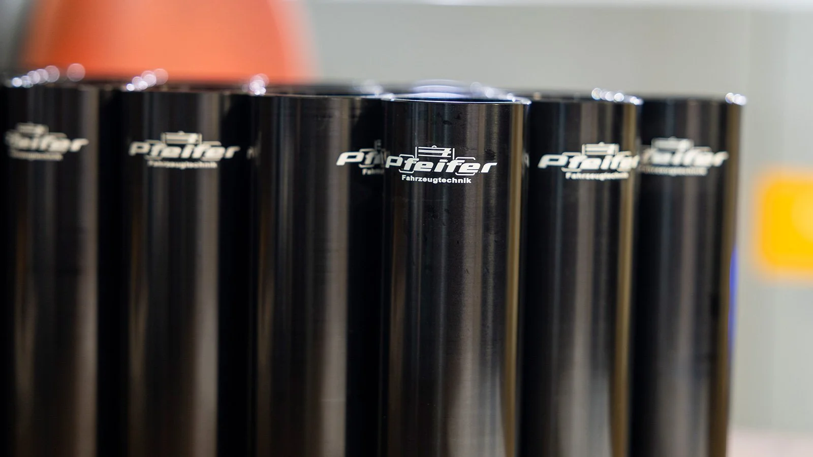 Mehrere schwarze Dosen mit dem Logo und Namen 'Platzer Fahrzeugtechnik' stehen nebeneinander.