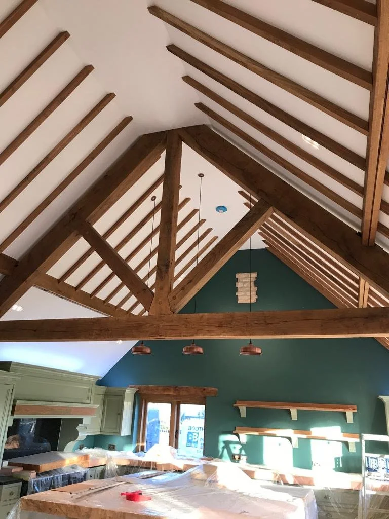 Interior of a room with high vaulted ceiling featuring exposed wooden beams and a green accent wall.