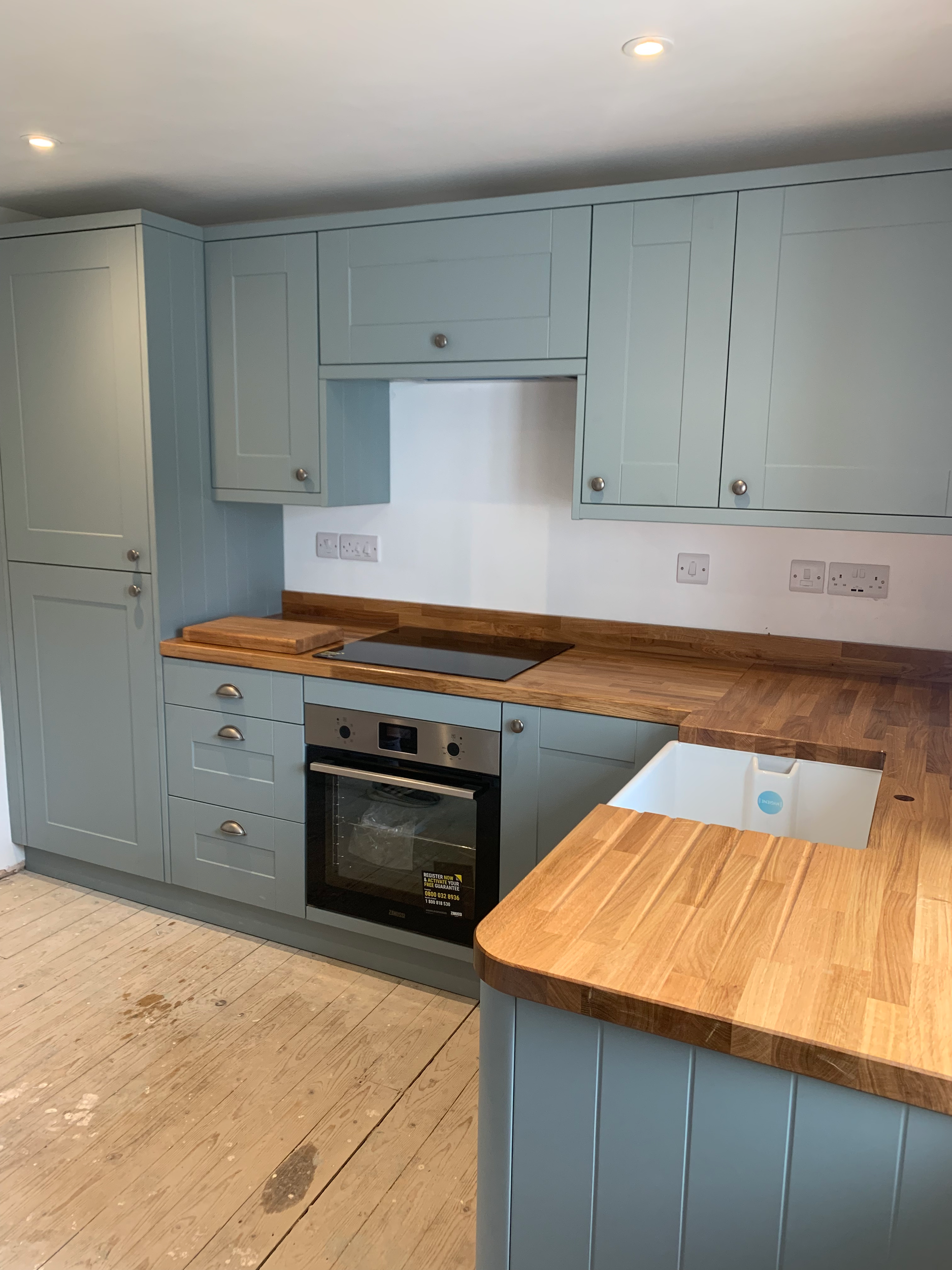 Kitchen with light blue cabinets, wooden countertops, a built-in oven, and a wooden wall on the floor.