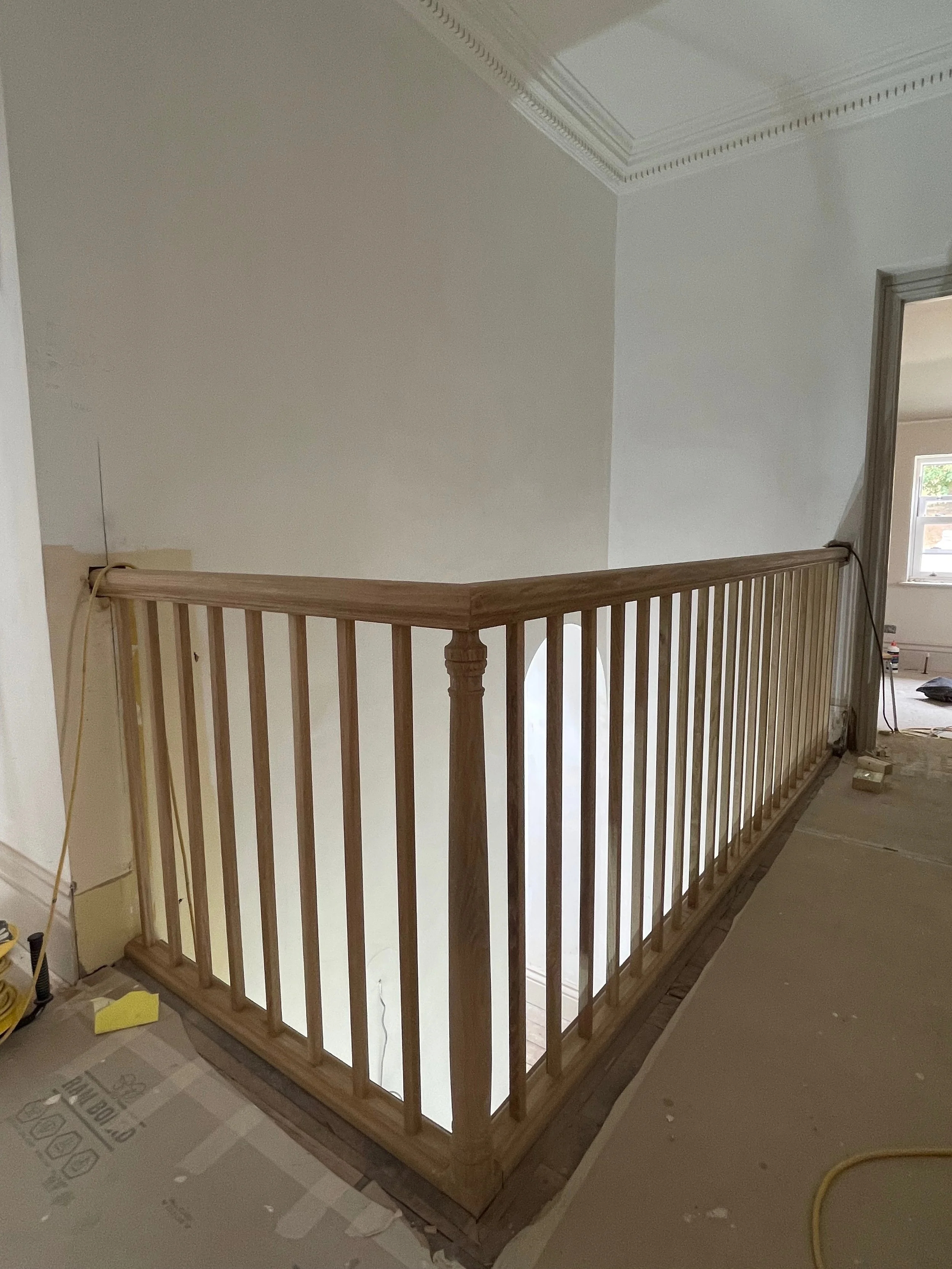 Wooden staircase railing under construction in a house interior.