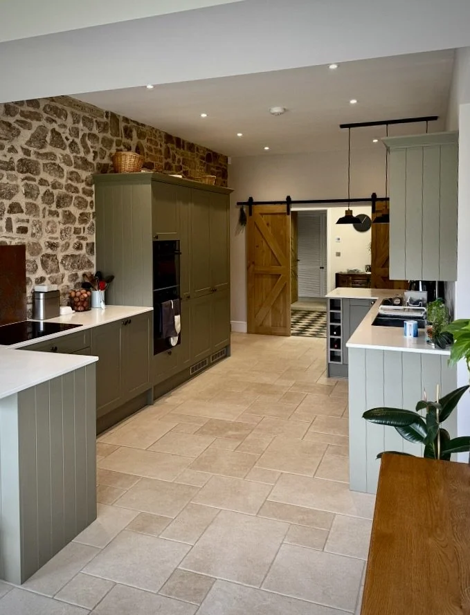 Modern kitchen with light grey cabinetry, stone accent wall, and wooden sliding barn doors.