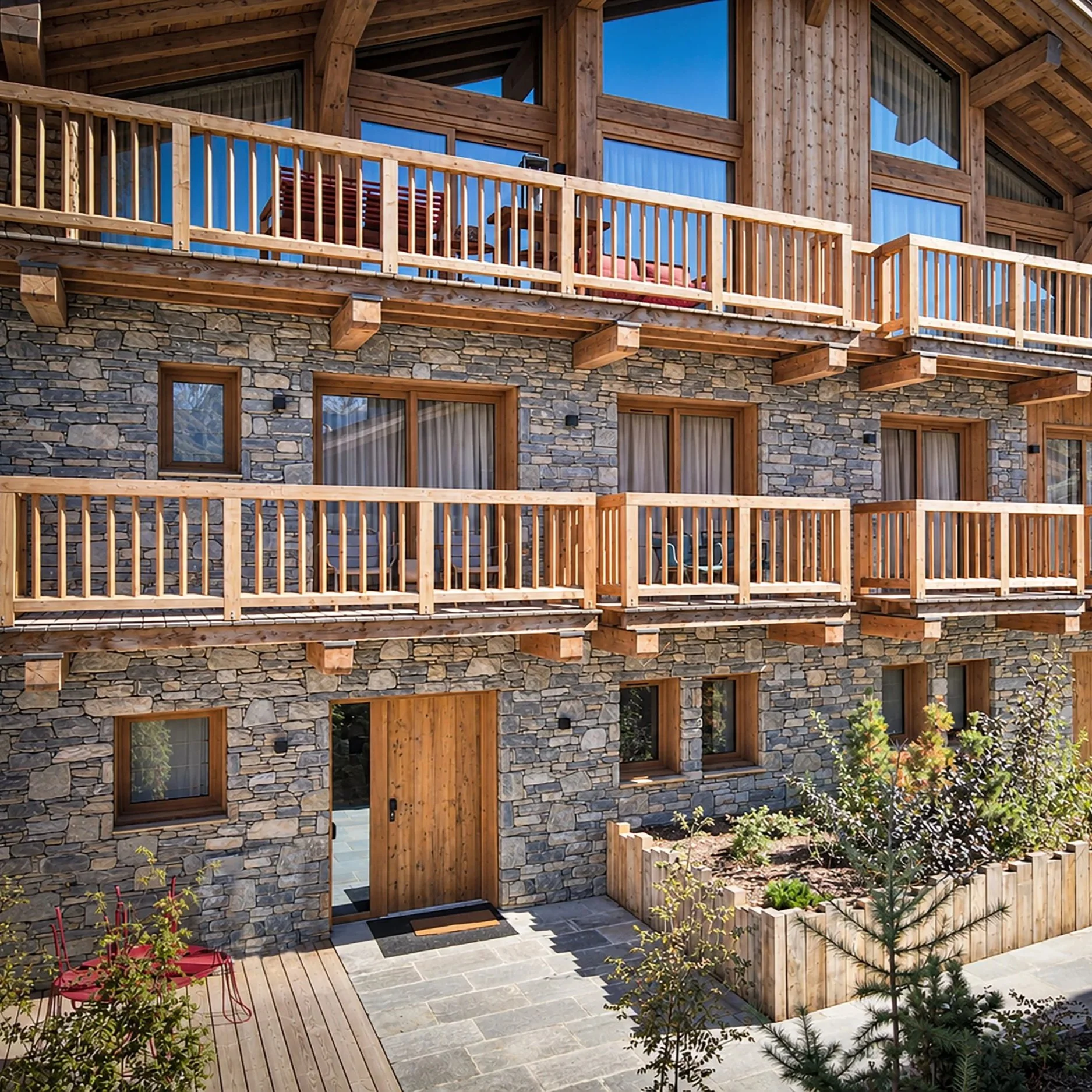 Façade en pierre et bois avec balcons et terrasses d'un chalet de standing de 337 m² à vendre près de Saint-Martin-de-Belleville, au cœur de la Vallée des Belleville.