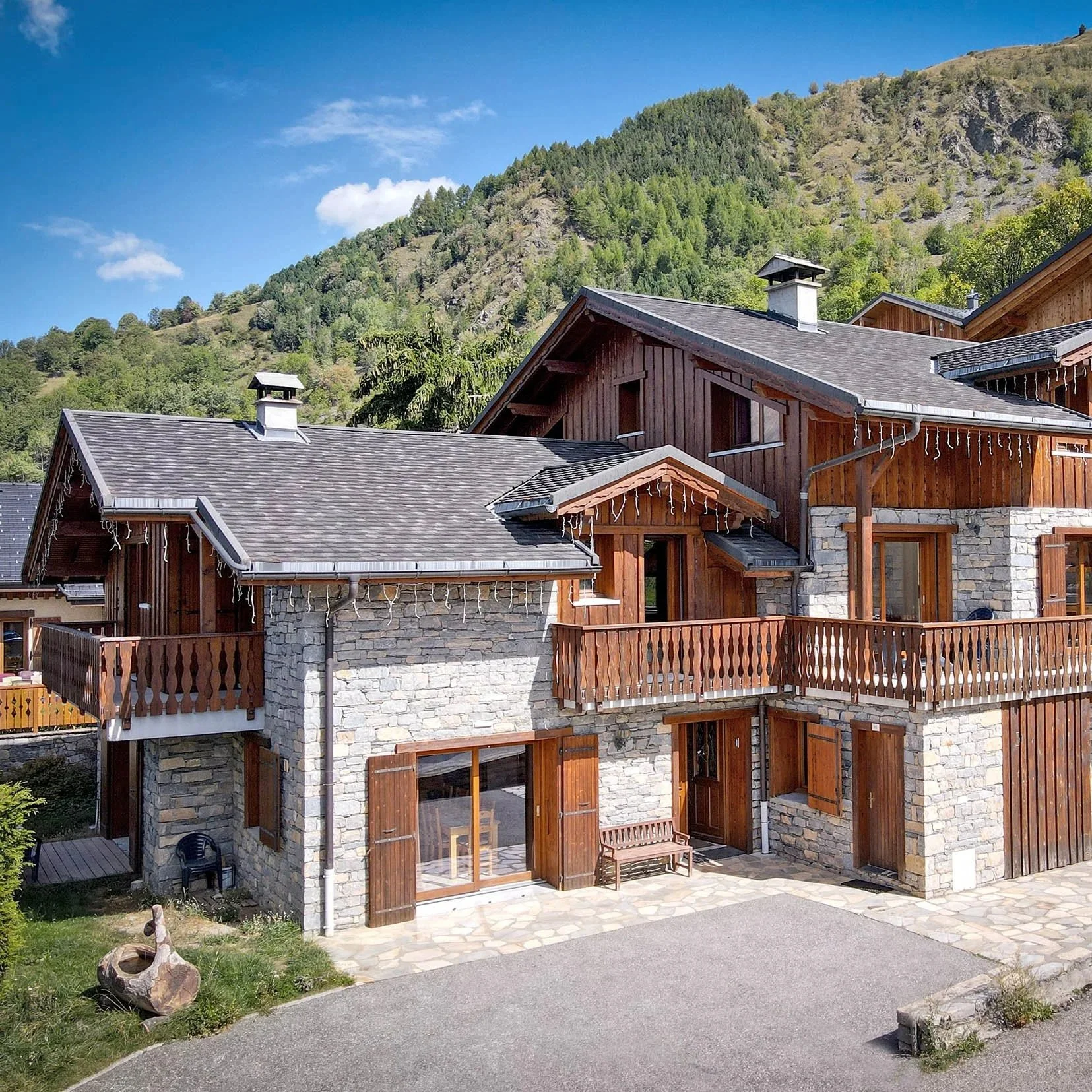 Façades en pierre et bois de deux chalets mitoyens avec balcons et terrasses, situés près de Saint-Martin-de-Belleville, au cœur des 3 Vallées.