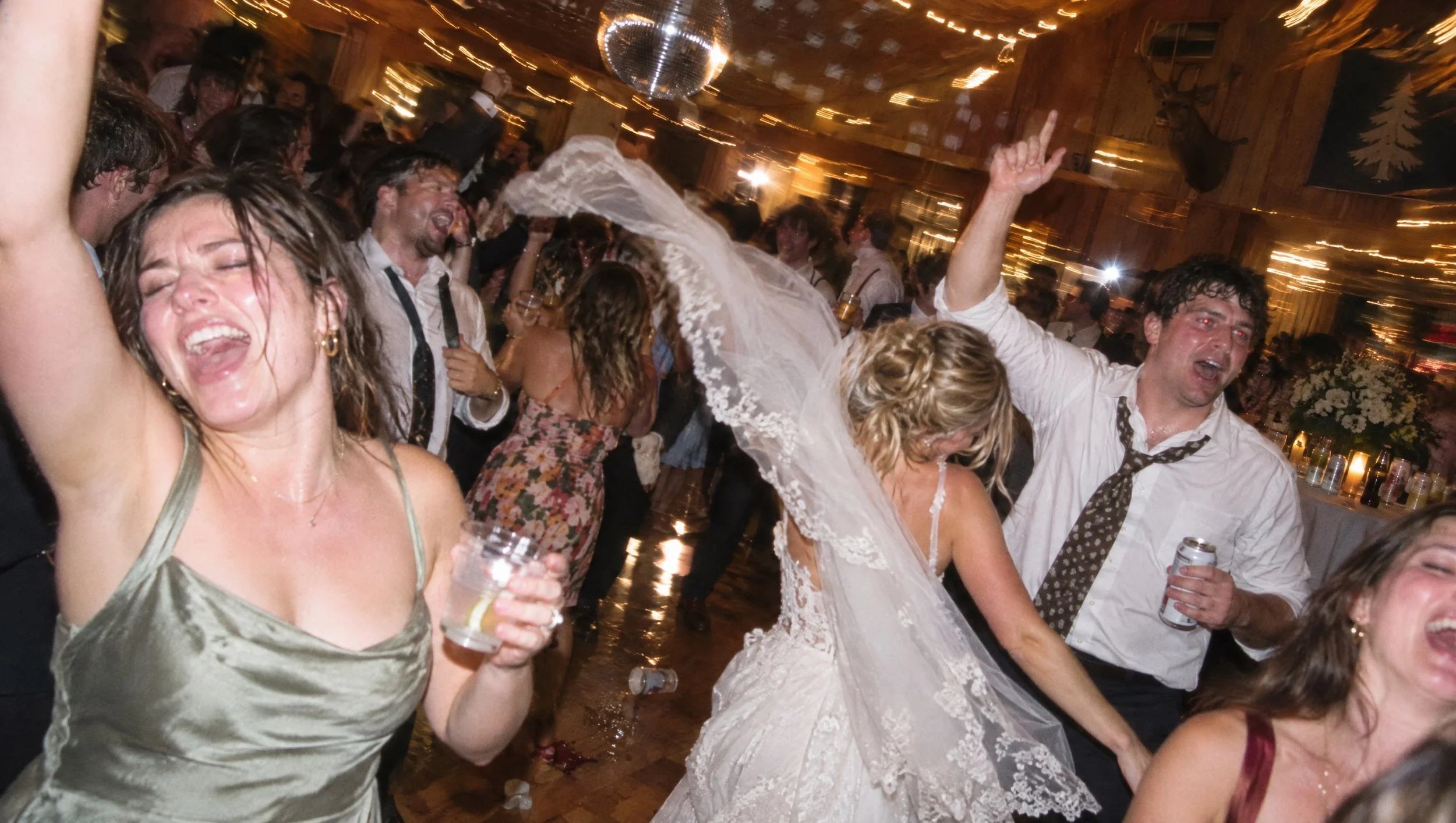 Guests dancing and cheering on a crowded wedding dance floor.