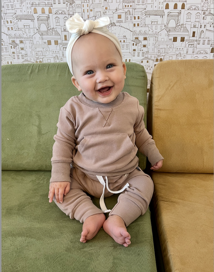 Smiling baby receiving gentle pediatric chiropractic care at home in Birmingham.