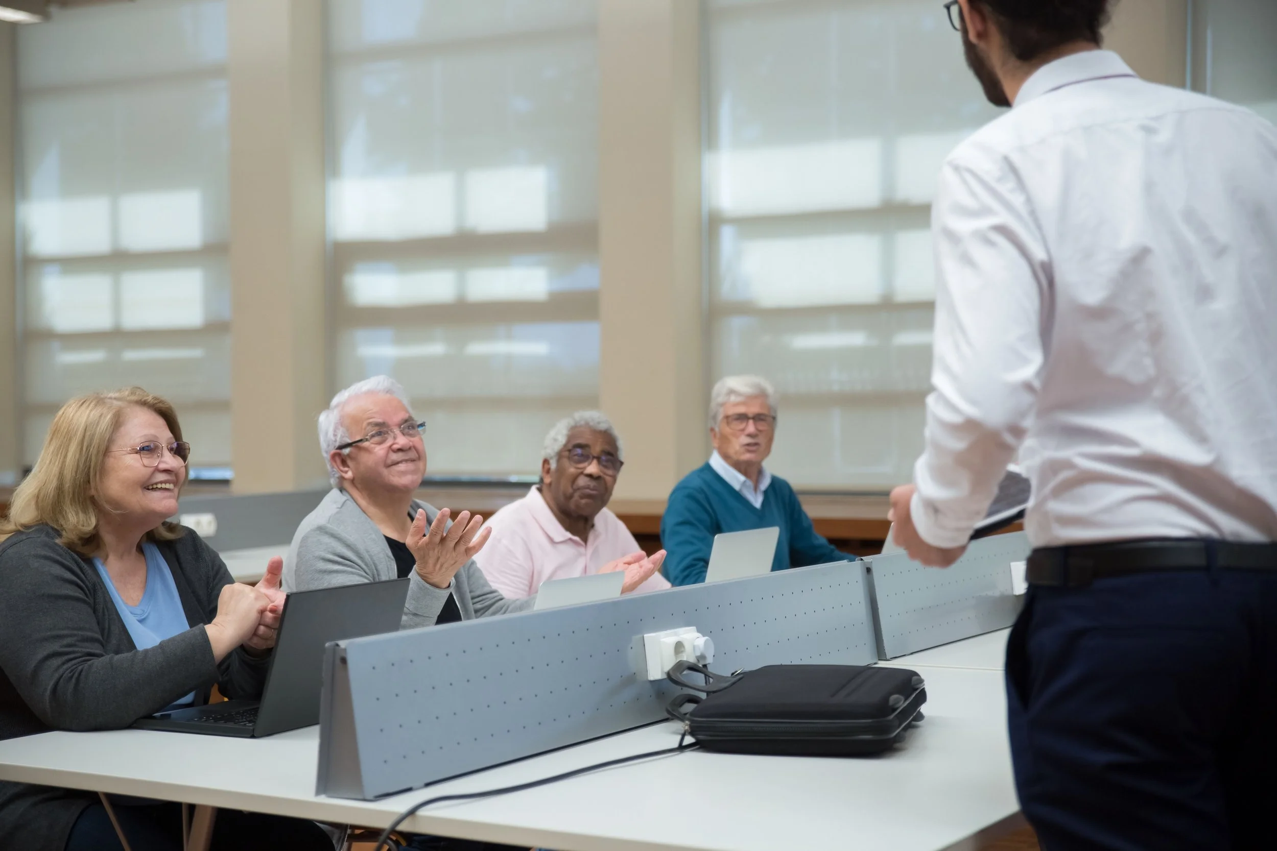 a professional standing facing towards four seated older adults at a table