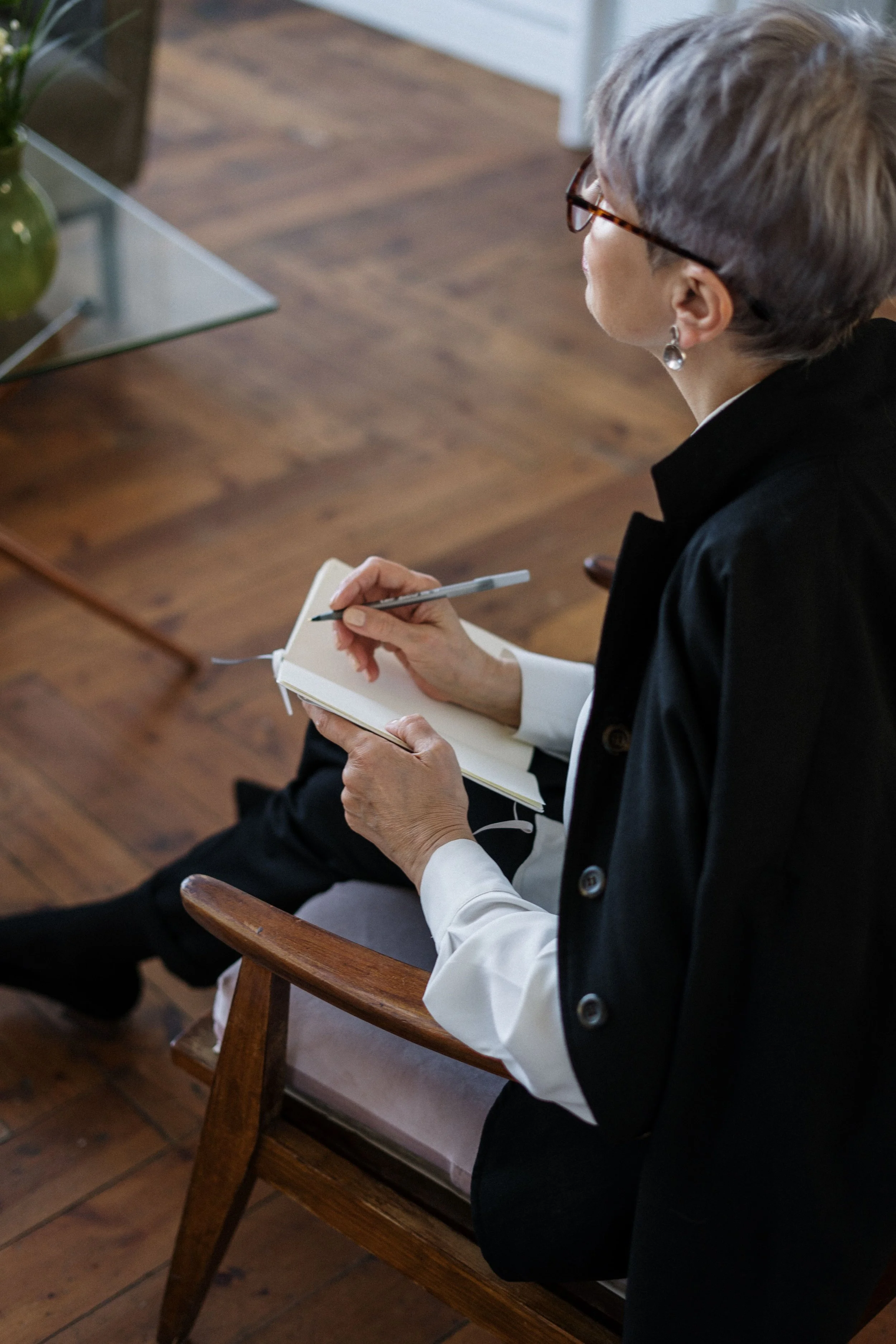 seated adult holding a notebook and pen