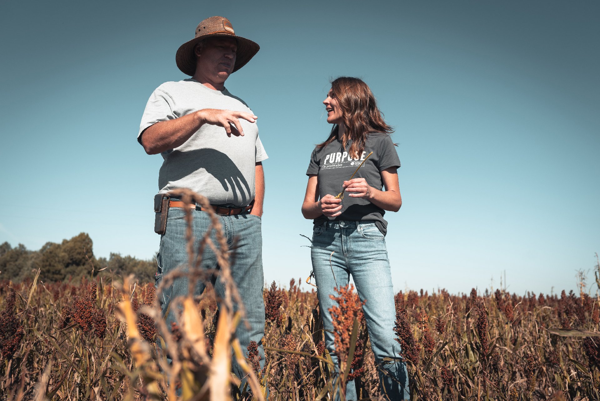 Kristine Root, Socha founder standing in sorghum field with Roy Pfaltzgraf