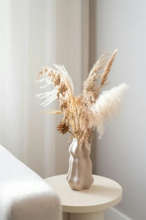 Dried grass in a vase in a white room.