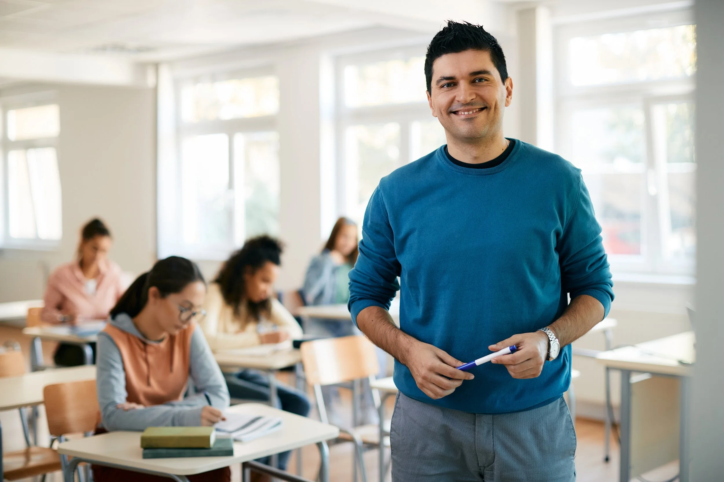 Teacher standing in a classroom while students work at their desks