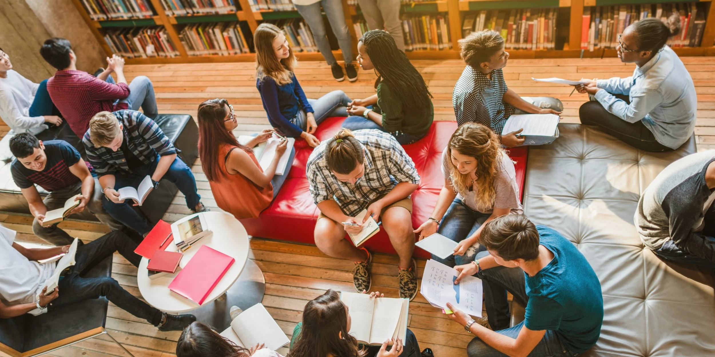 Diverse group of teens reading books in library
