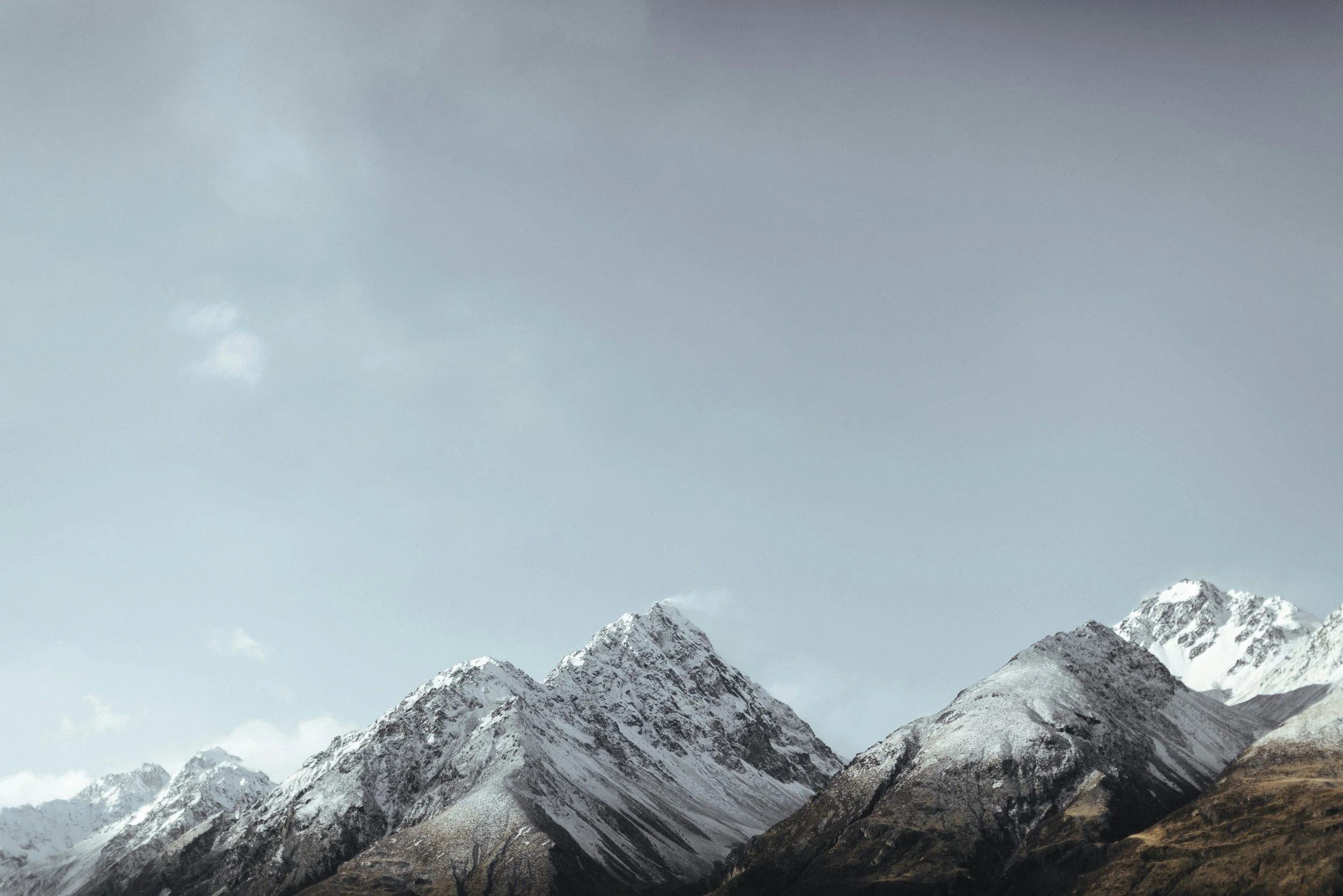 Snow-capped mountain peaks under a cloudy sky.