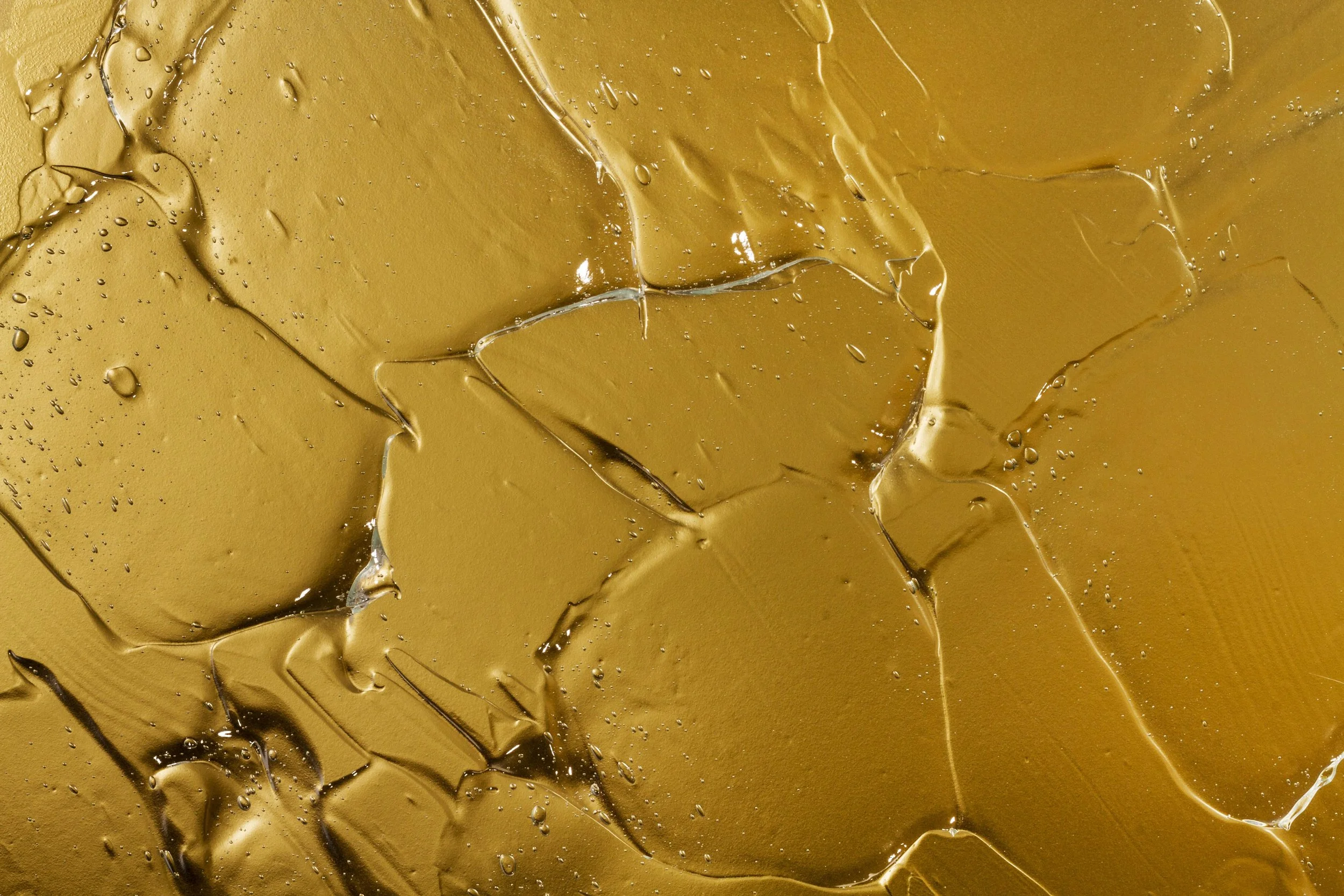 Close-up of melted caramel spread on a surface, with swirls and tiny bubbles.