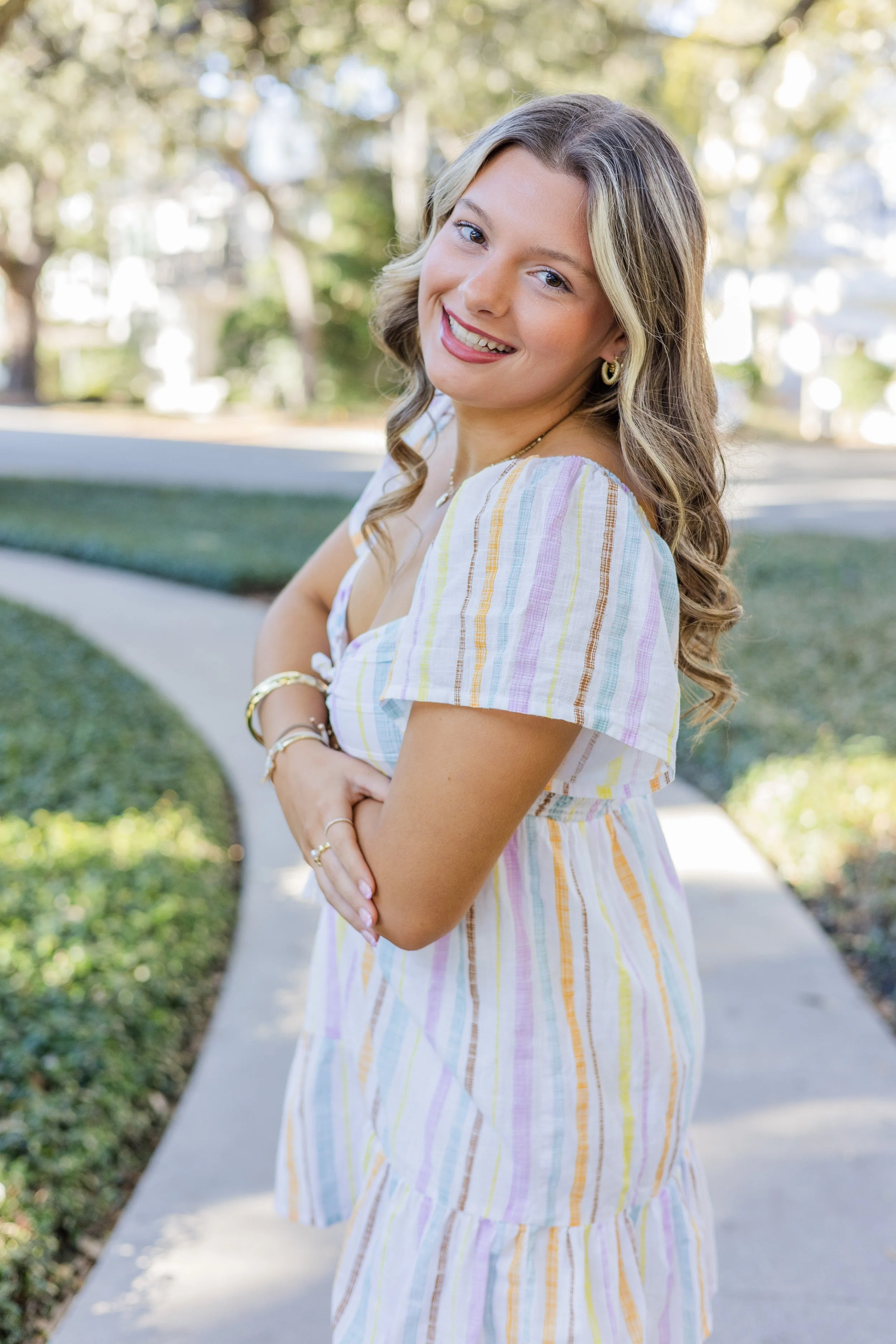 senior girl in multi colored stripe dress with arms crossed on st Simons island